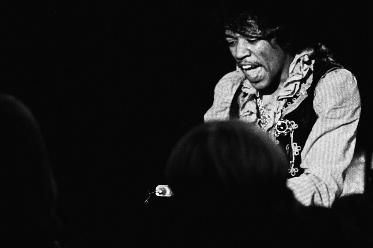 An exalted Jimi Hendrix, on his knees, calls out as he sprays lighter fluid on his guitar on stage at Monterey Pop.