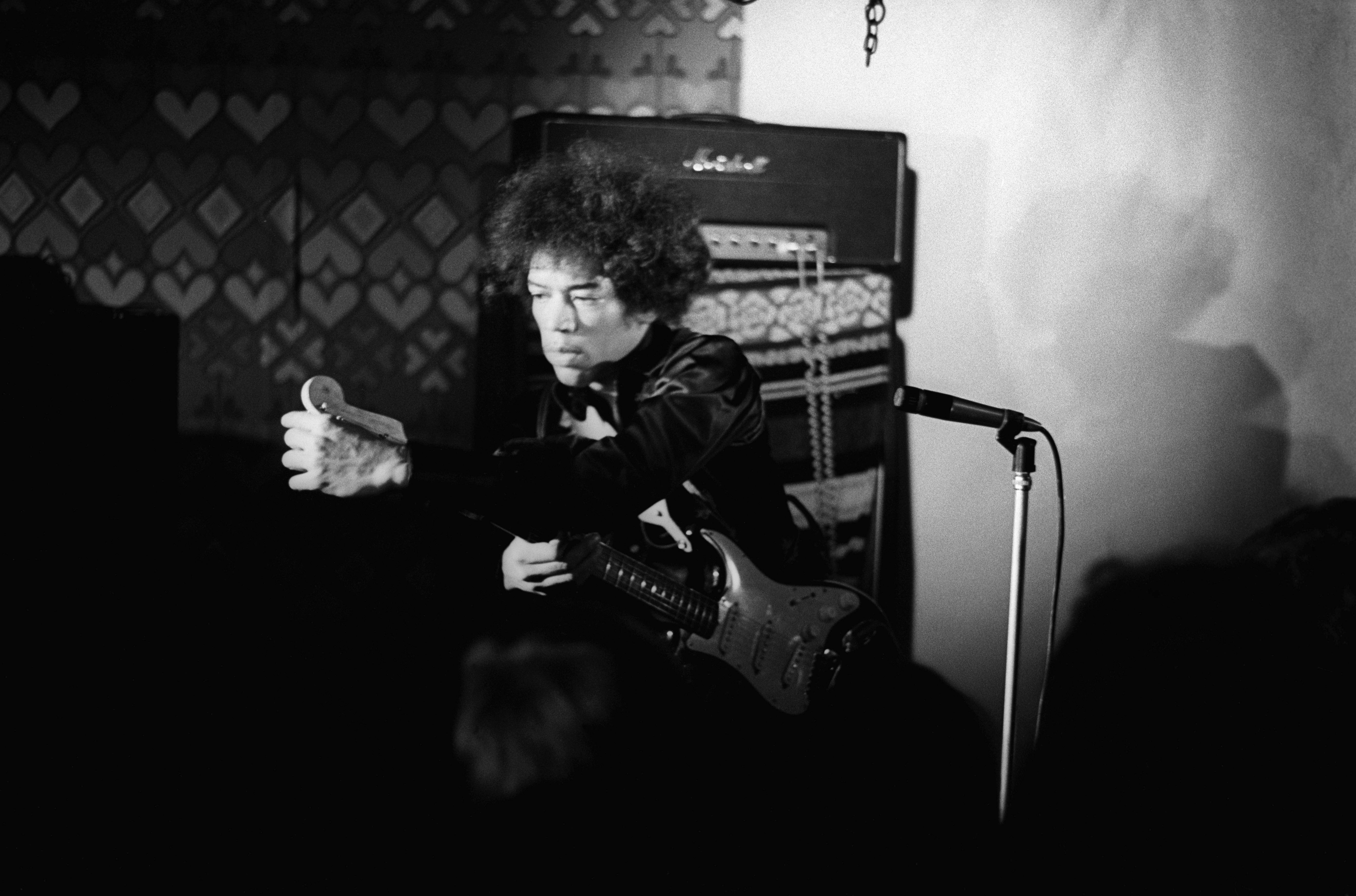 Jimi Hendrix tunes his guitar on stage in 1967.