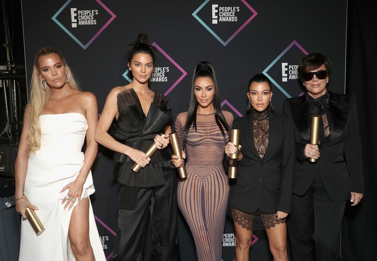 Khloé Kardashian, Kendall Jenner, Kim Kardashian, Kourtney Kardashian, and Kris Jenner posing for a photo at an award show after winning a trophy
