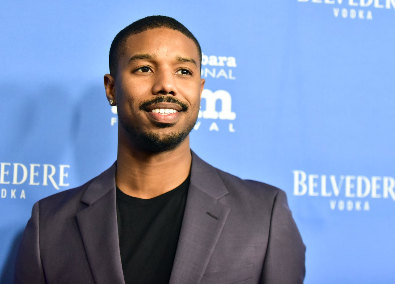 Michael B. Jordan smiling in front of a blue backdrop