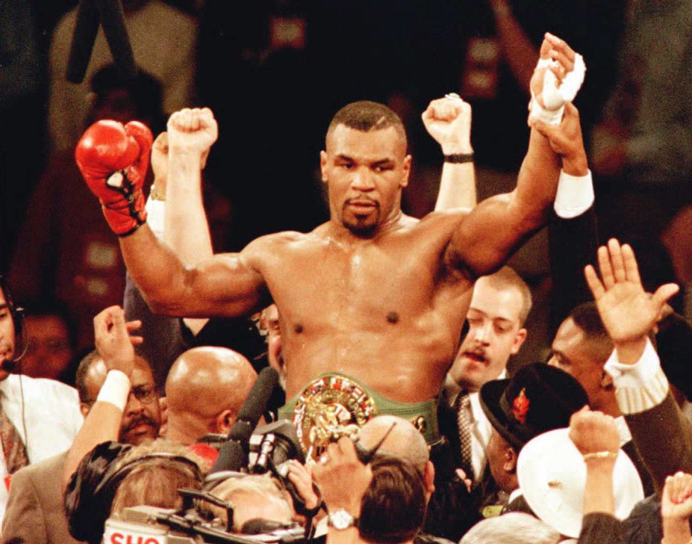Mike Tyson is lifted into the air wearing the championship belt after defeating WBC heavyweight champion Frank Bruno