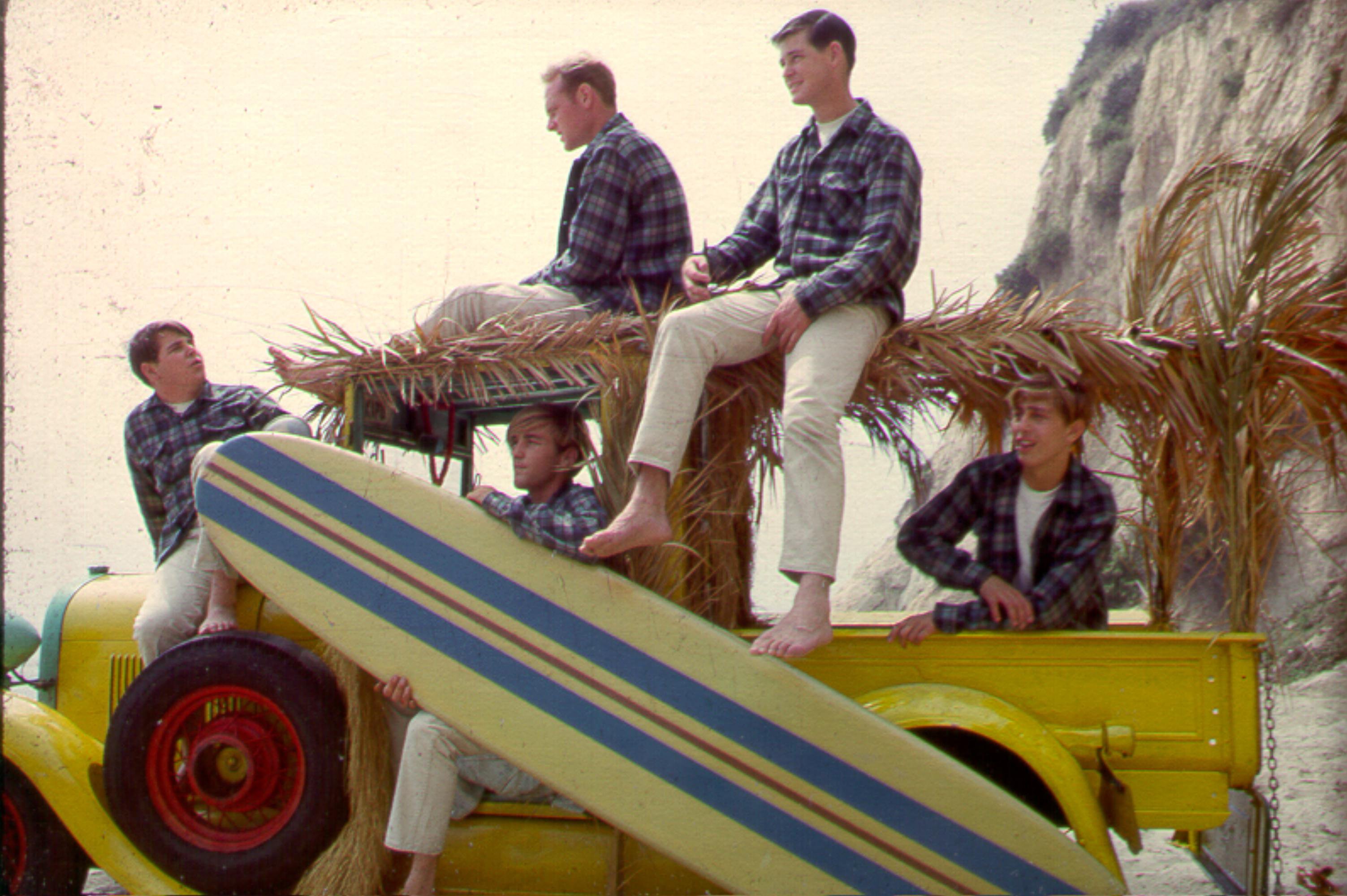 The Beach Boys sitting on a truck at a beach