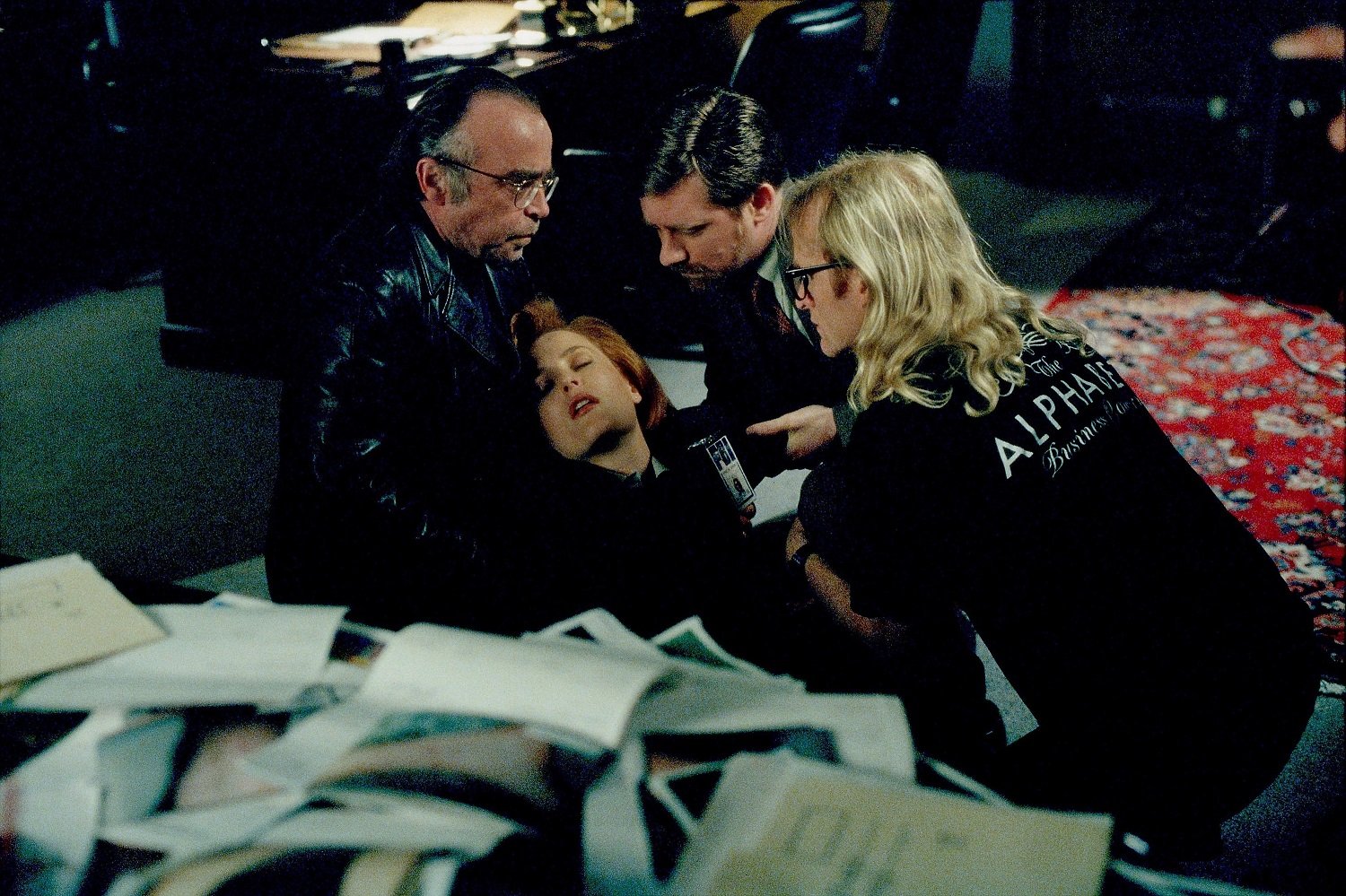 Agent Scully (Gillian Anderson, C) is saved from a fall by The Lone Gunmen (L-R: Tom Braidwood as Frohike, Bruce Harwood as Byers, and Dean Haglund as Langley) in The X-Files