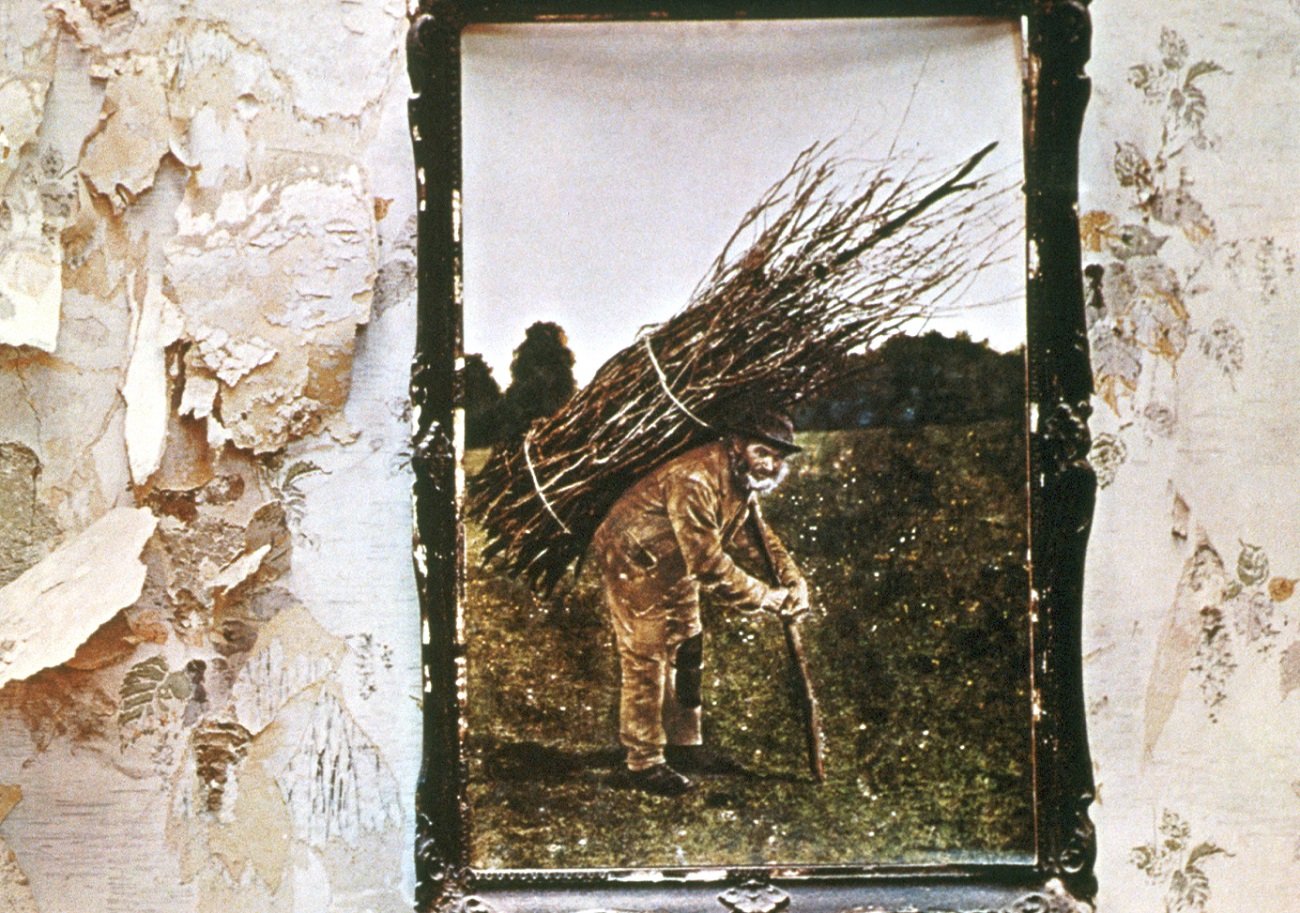 Detail of the 'Led Zeppelin IV' cover featuring a framed painting of an old man with a cane carrying a bundle of twigs on his back  