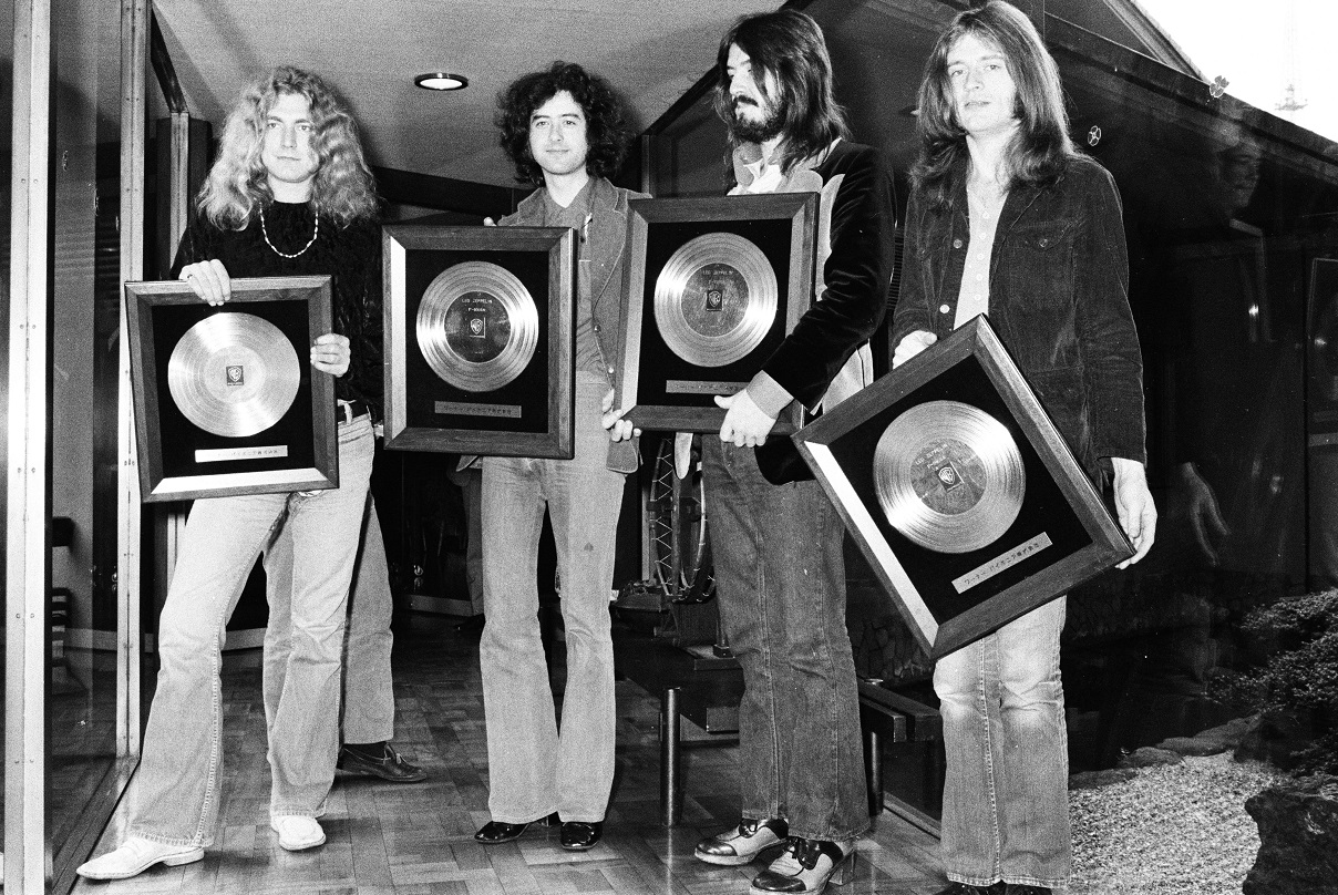 The four members of Led Zeppelin hold framed gold records and smile for the camera in 1972.