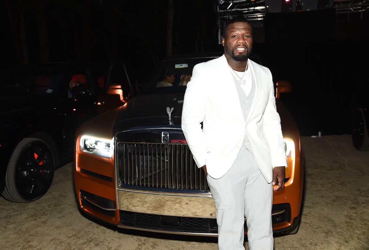 Curtis "50 Cent" Jackson dressed in white standing in front of a Rolls Royce