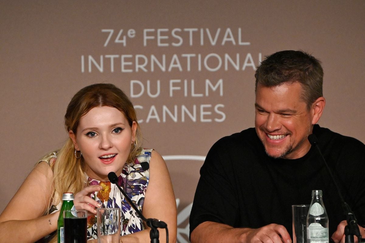 Abigail Breslin speaks into a mic while Matt Damon smiles during a 'Stillwater' press conference at the 2021 Cannes Film Festival