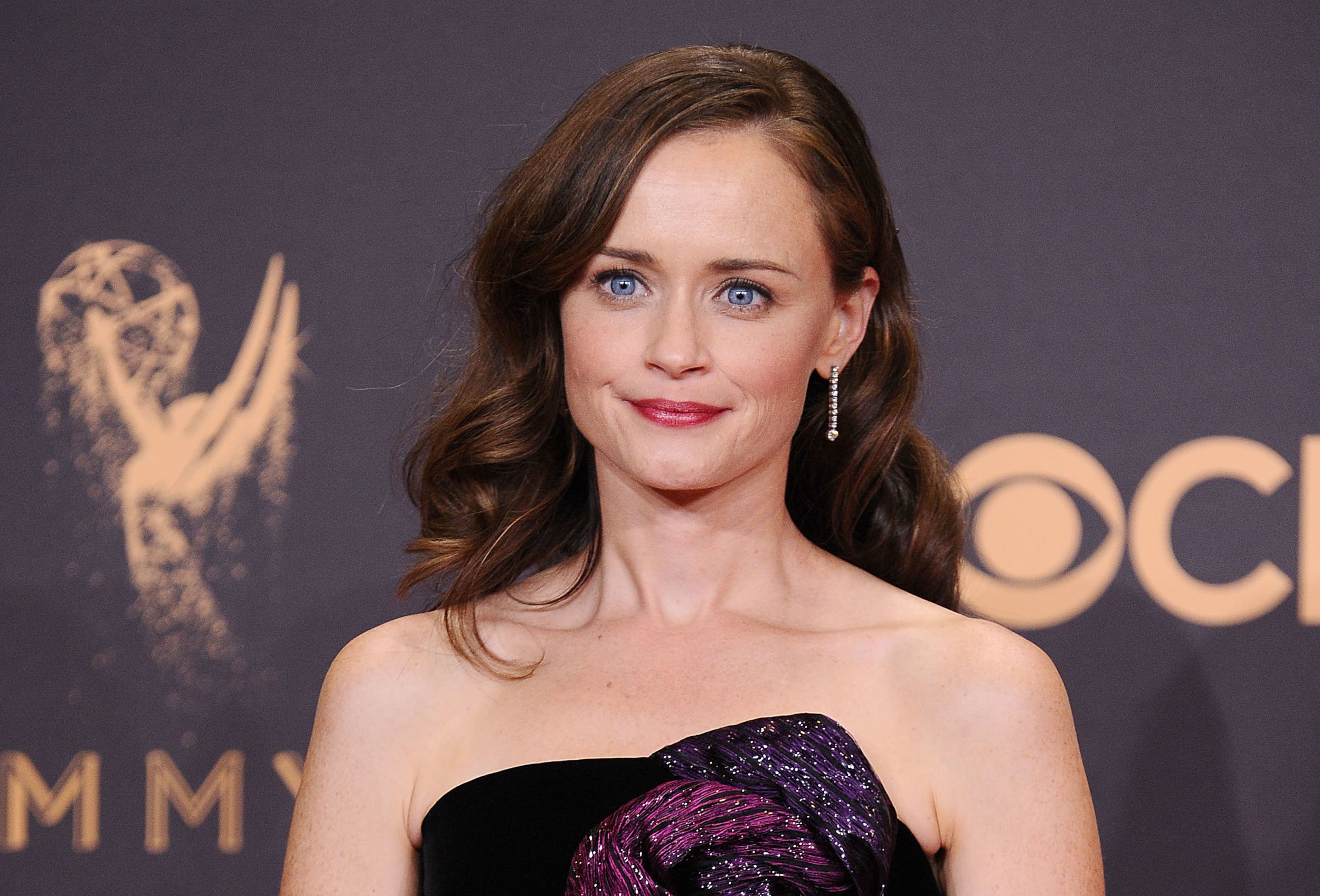'Gilmore Girls' star Alexis Bledel wears a purple dress and stands in front of an Emmy wall
