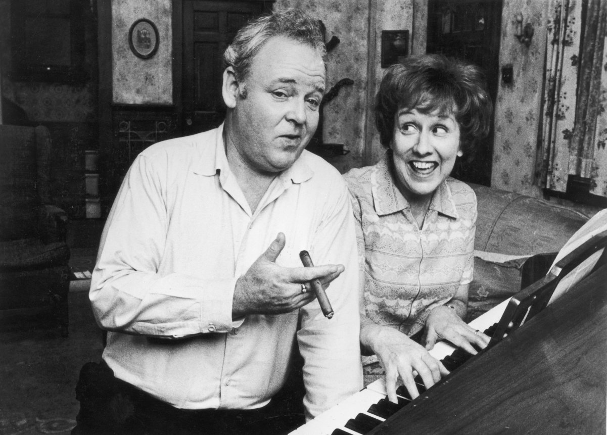 Actors Carroll O'Connor and Jean Stapleton pose by a piano as Archie and Edith Bunker in a scene from 'All in the Family'