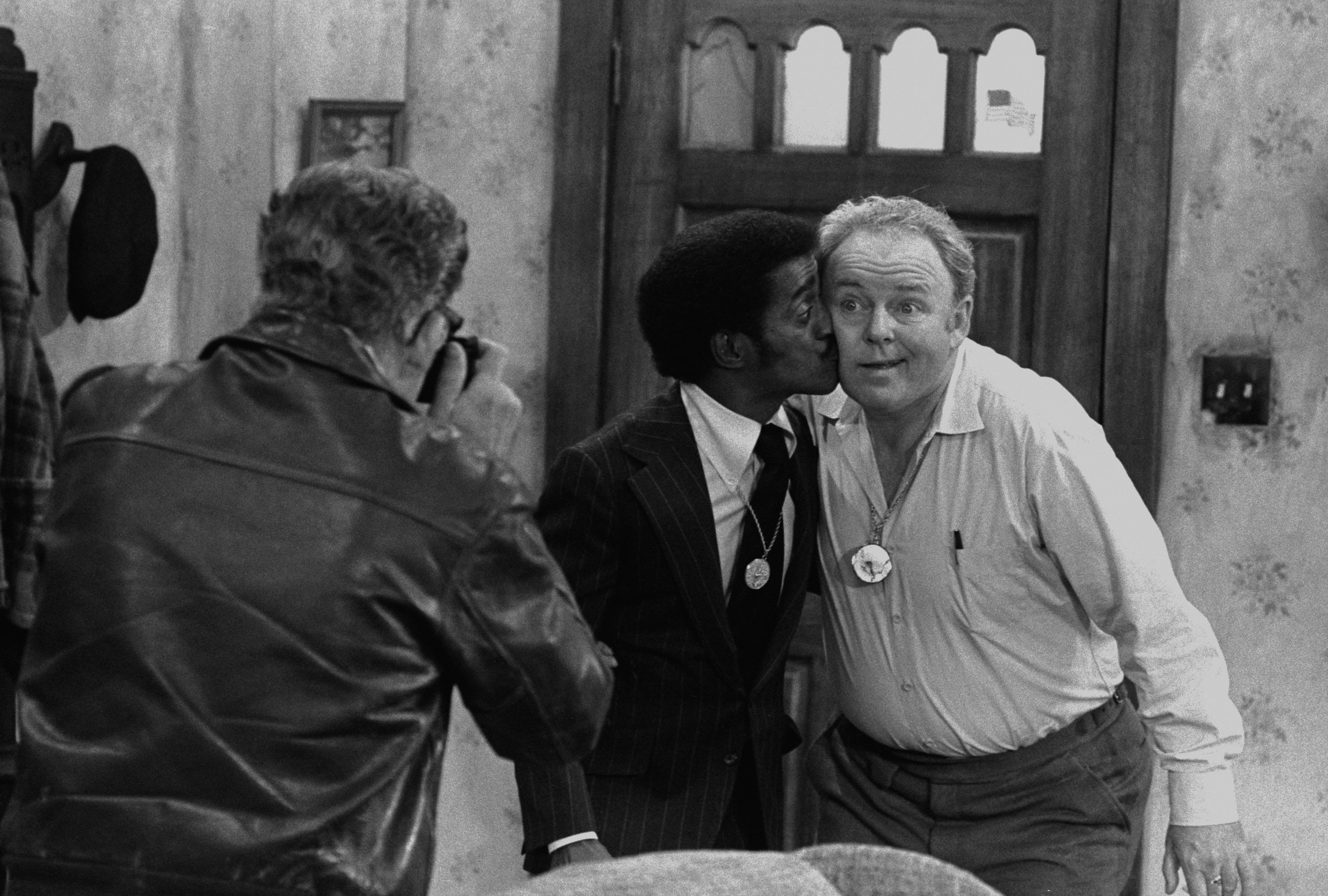 Actor Billy Halop (with camera), entertainer Sammy Davis Jr., and actor Carroll O'Connor in a scene from 'All in the Family'