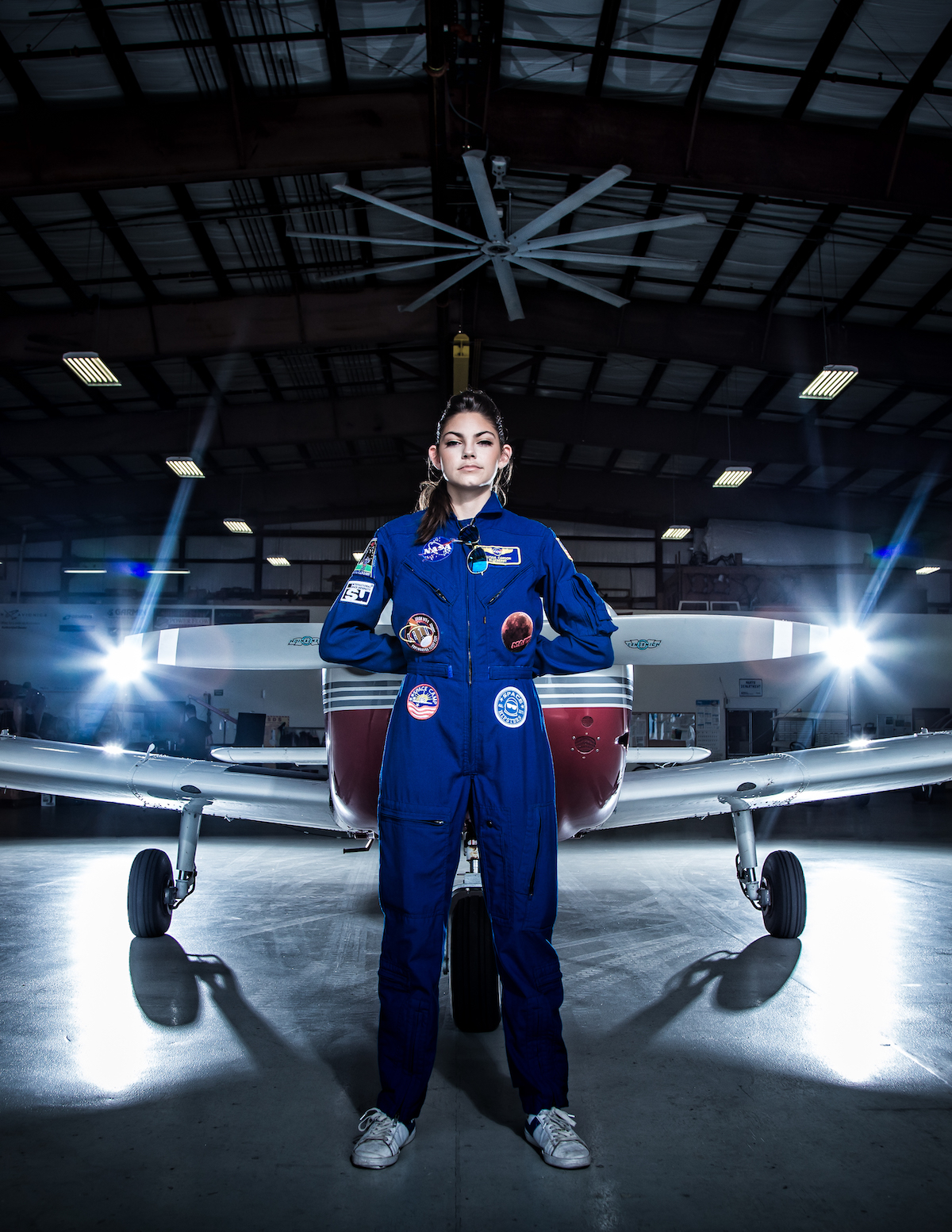 Astronaut Alyssa Carson wearing a blue flight suit and standing in front of a plane