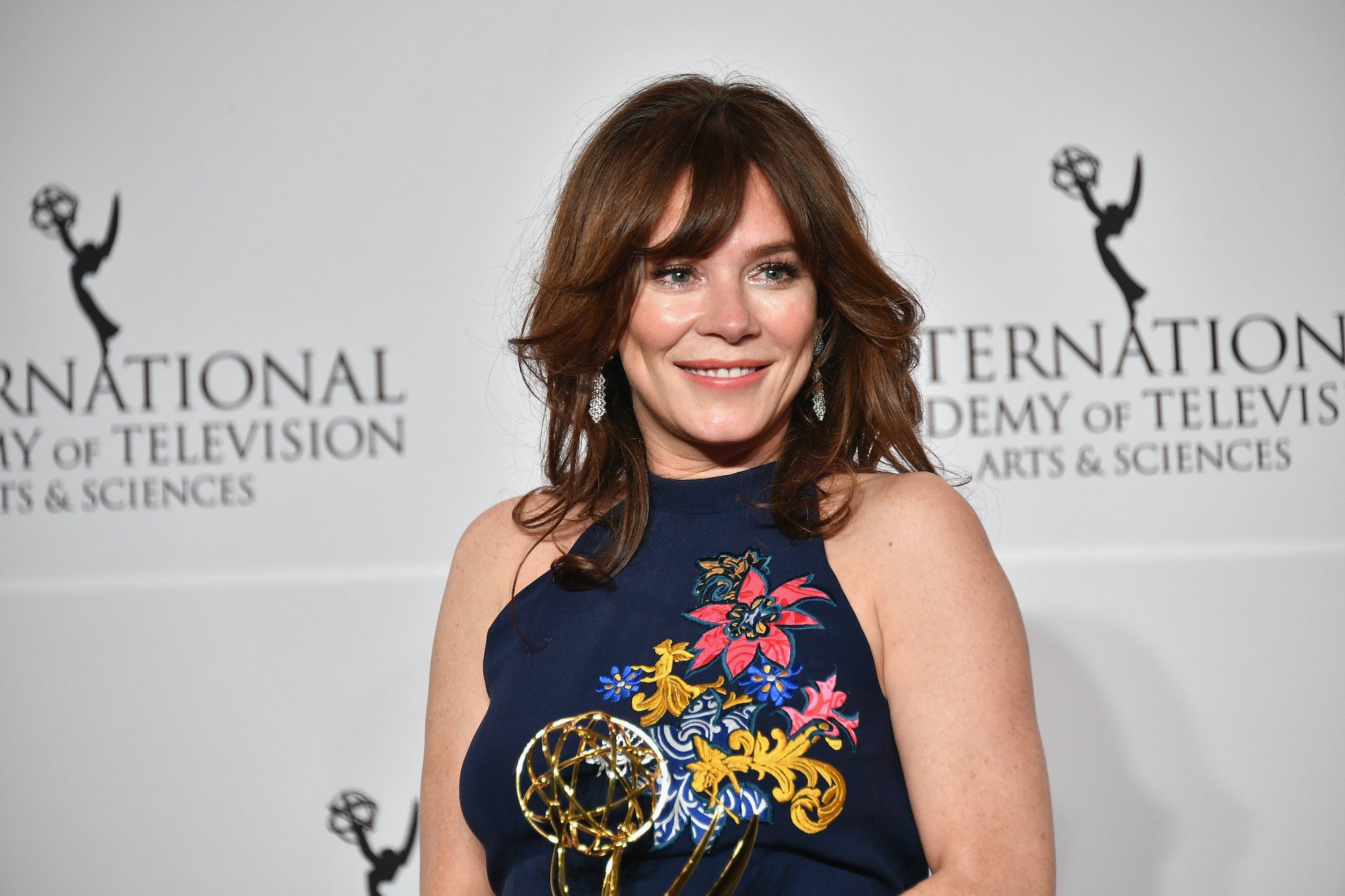 Anna Friel smiling in front of a white background