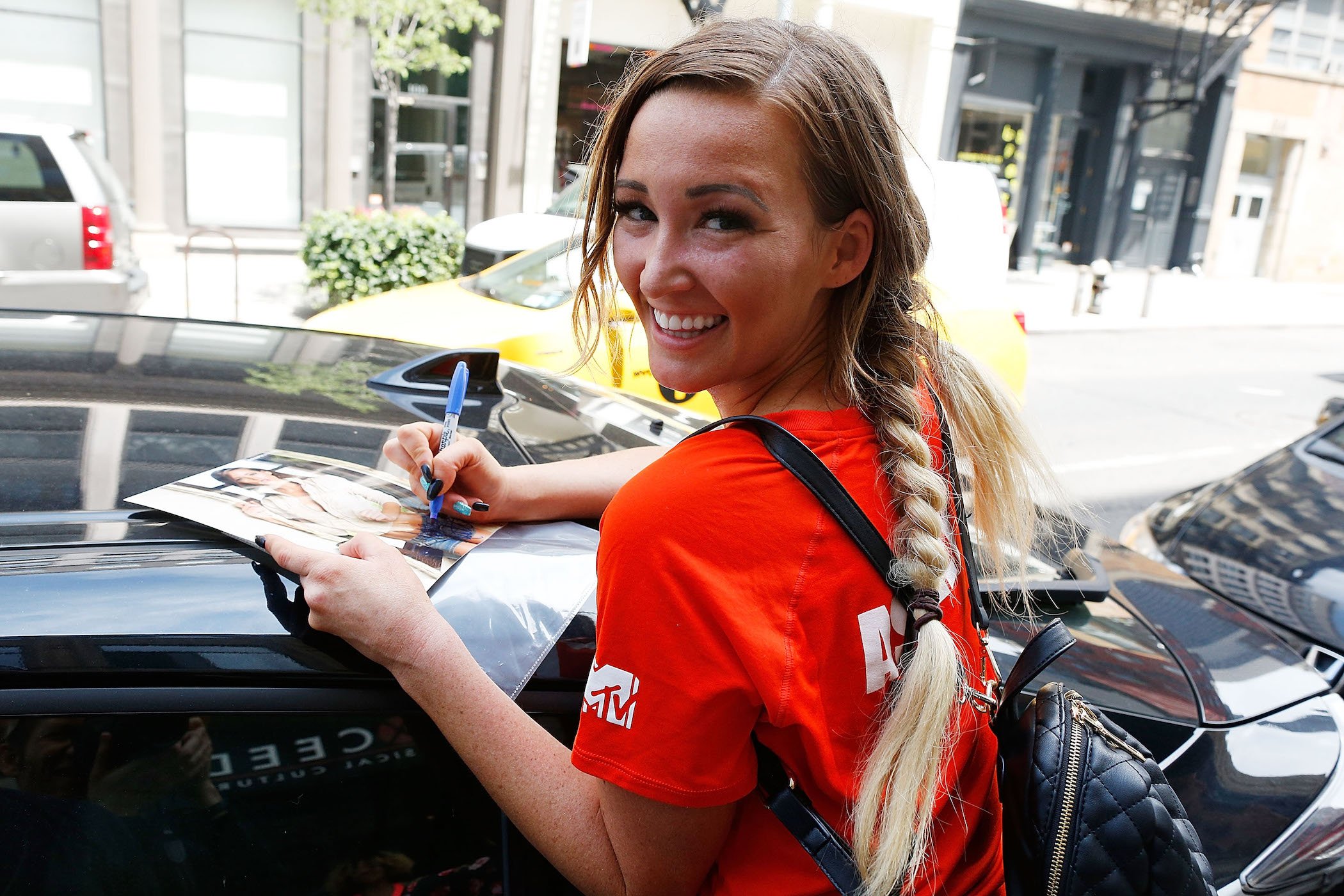 Ashley Mitchell from 'The Challenge' Season 37 smiling while signing an autograph at MTV's 'The Challenge' XXX: Ultimate Fan Experience