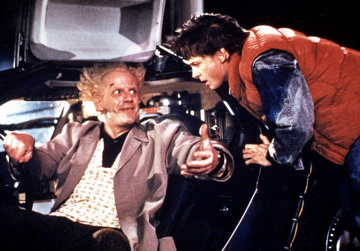 Doc Brown (Christopher Lloyd) sits in the Delorean smiling up at Mary McFly (Michael J. Fox) in ‘Back to the Future’