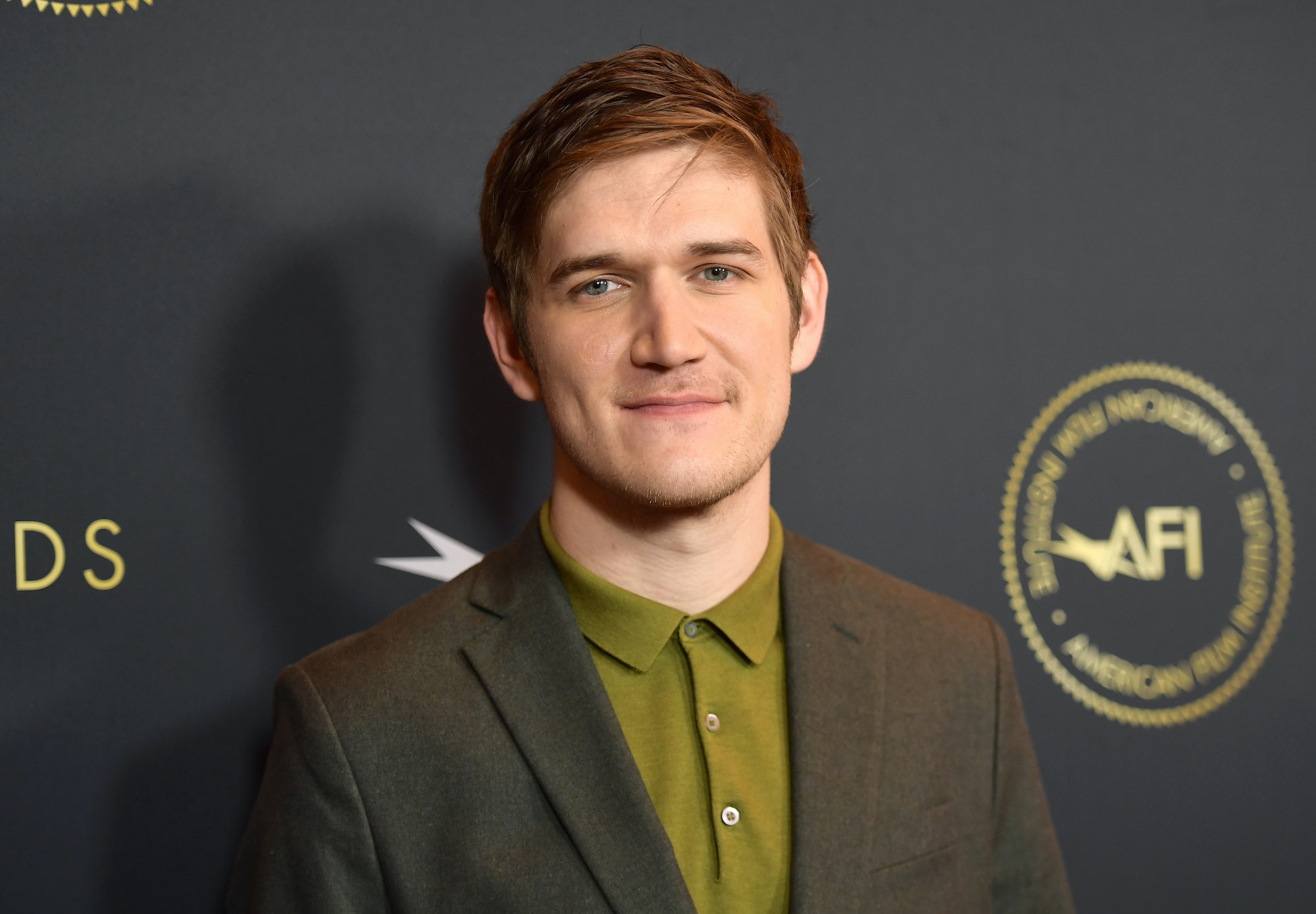 Bo Burnham smiling in front of a gray background