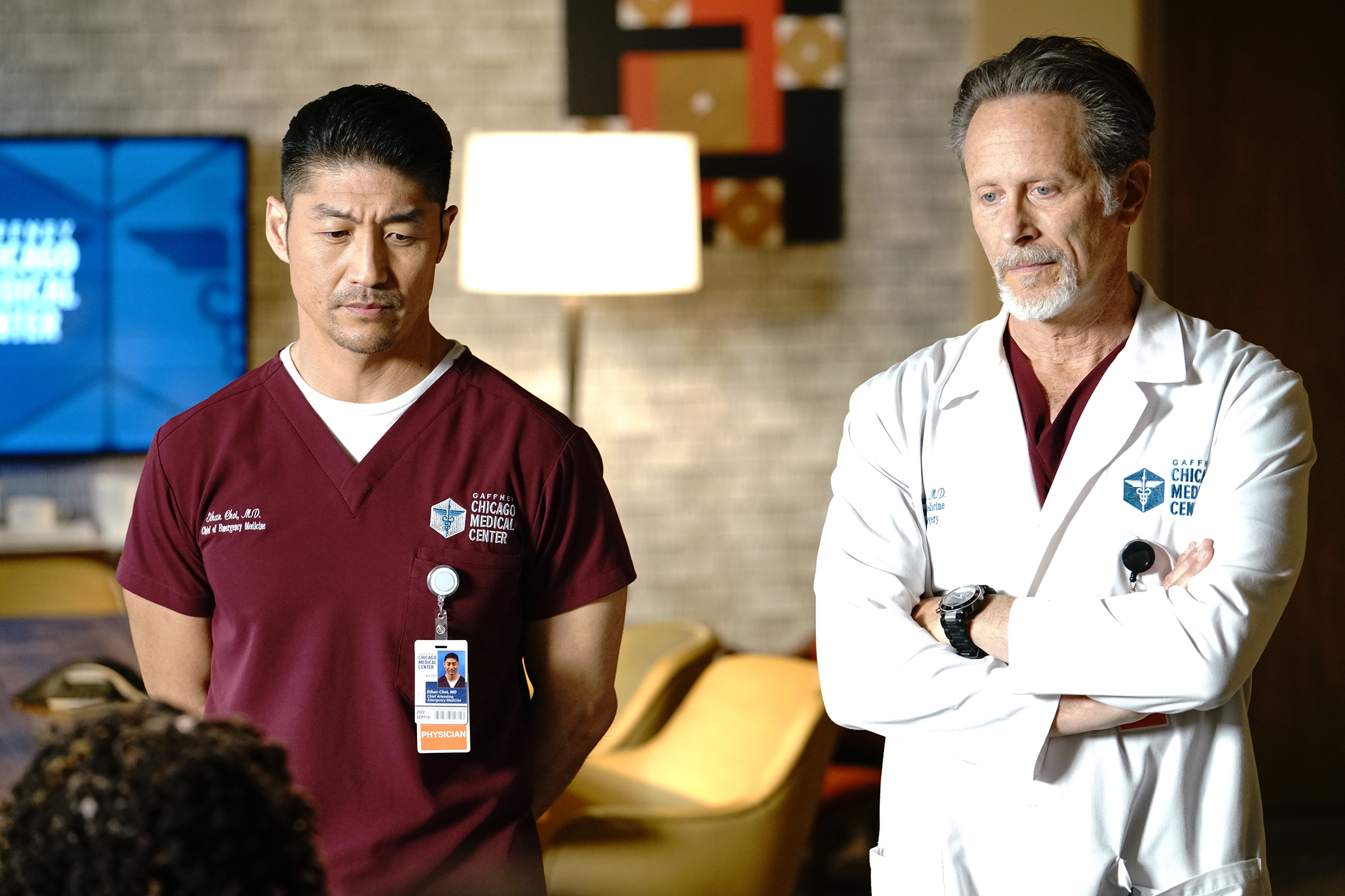 Brian Tee and Steven Weber stand next to each other in an office on the set of 'Chicago Med'
