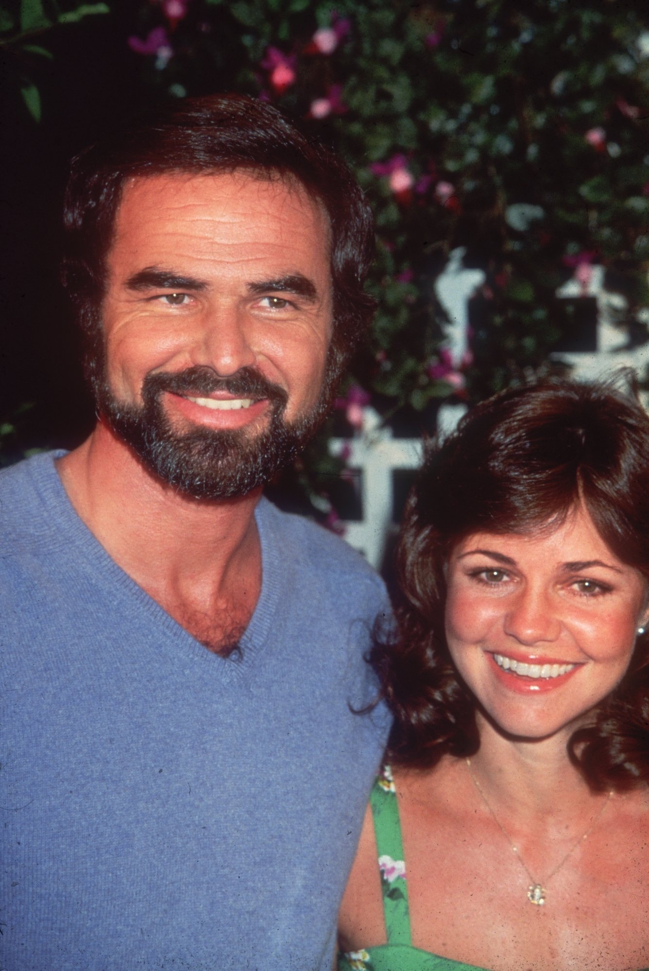Burt Reynolds and Sally Field posing together at an outdoor event in 1977