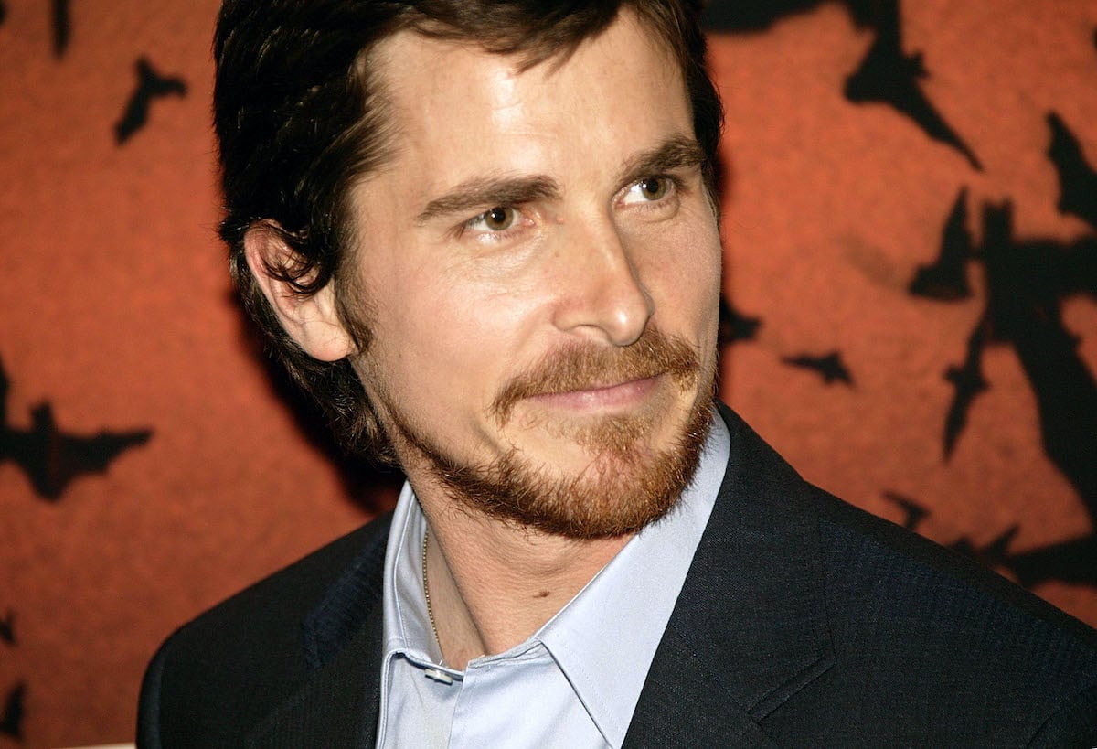 Christian Bale smiles in a dark suit at the European premiere of ‘Batman Begins’