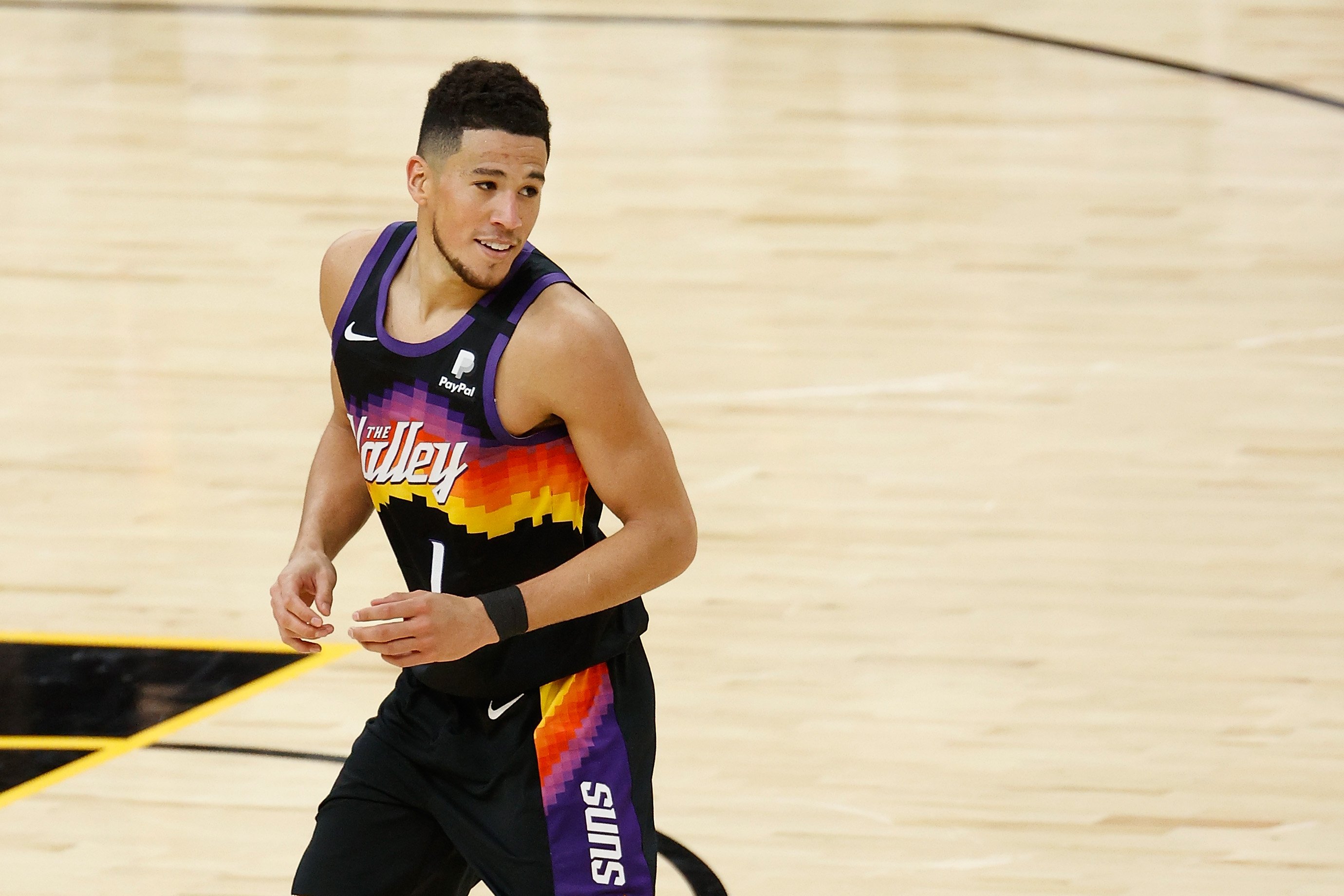 Devin Booker giving a slight smile after a three-point shot in a game against the Philadelphia 76ers