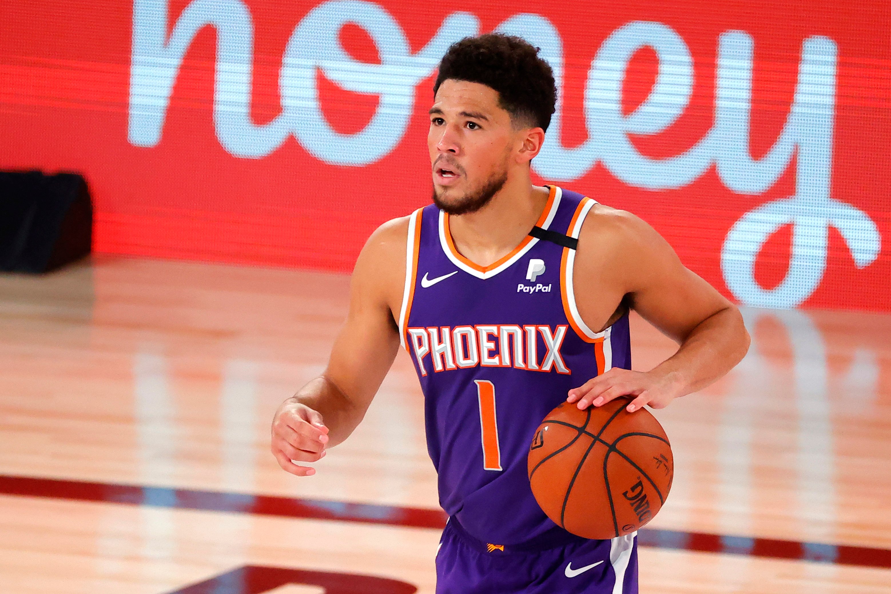 Devin Booker of the Phoenix Suns dribbling a basketball downcourt during a game against the LA Clippers