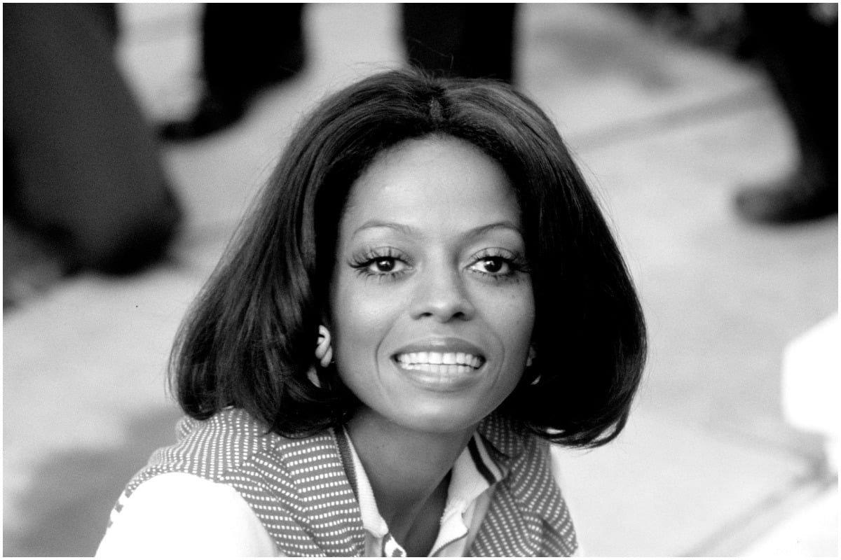 Diana Ross smiling at the camera in a black-and-white photo.