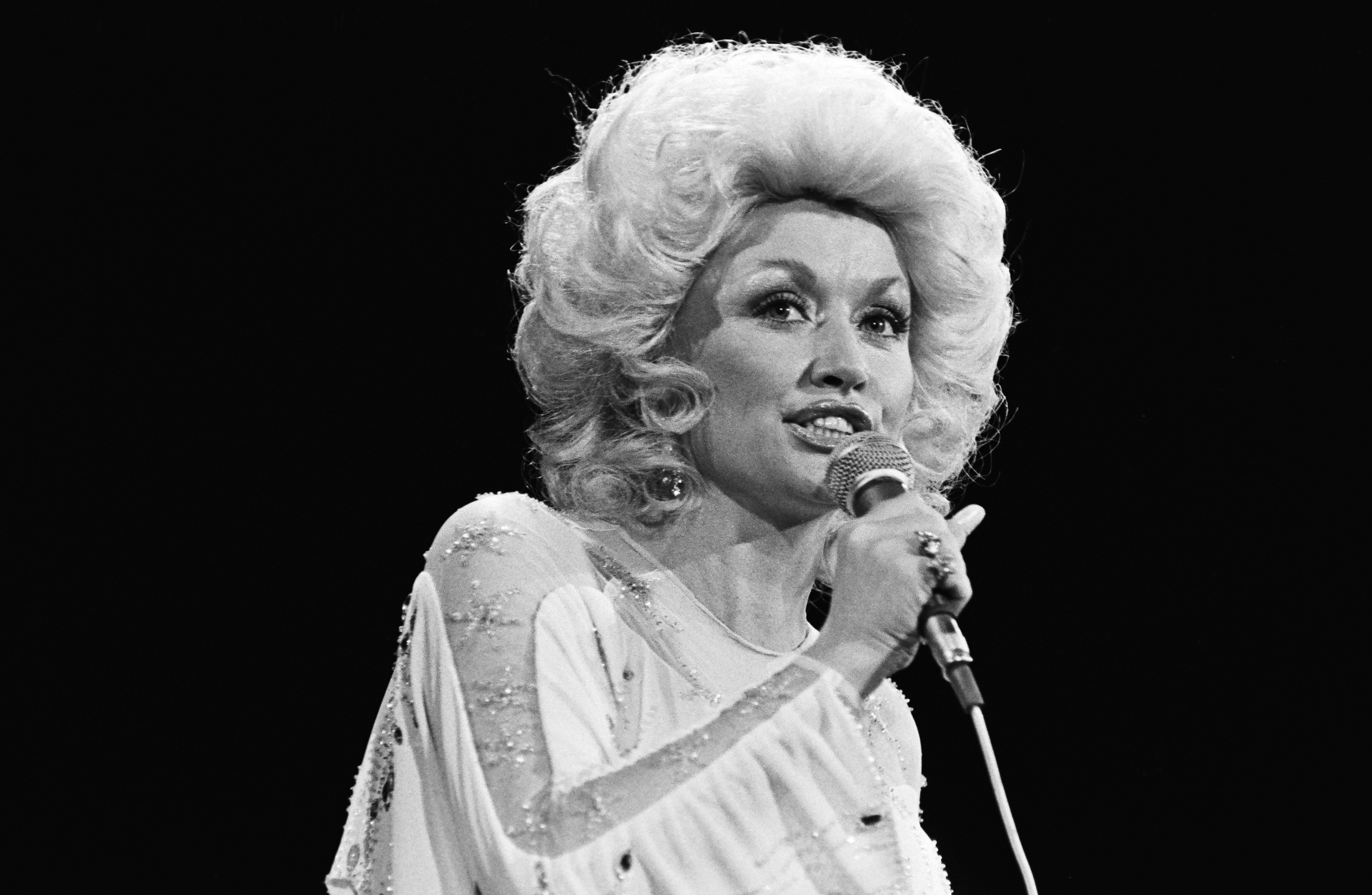 Dolly Parton singing into a microphone. The shot is black and white. The year is 1981.