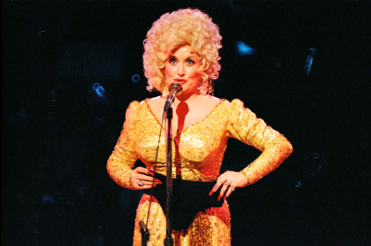 Dolly Parton holds up a pair of underwear in front of her yellow outfit on stage at The Dominion Theatre