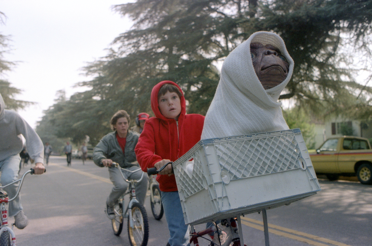 Henry Thomas wears a red hoodie and rides a bike with E.T. in a scene from ‘E.T. the Extra-Terrestrial’