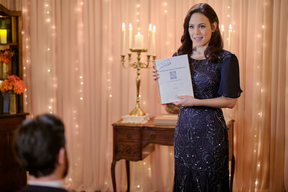 Erin Krakow as Elizabeth holding a copy of her novel manuscript in 'When Calls the Heart'