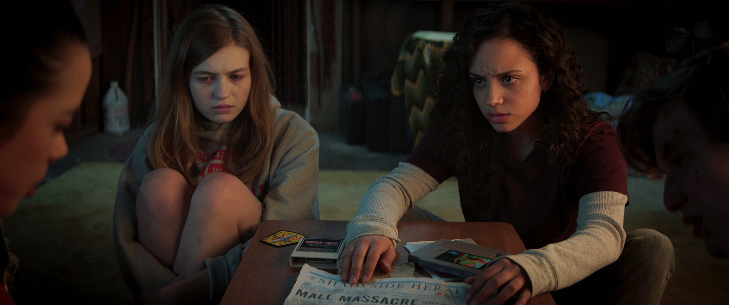 Netflix's 'Fear Street' stars Olivia Scott Welch and Kiana Madeira looking at a newspaper in Part 1 of the series