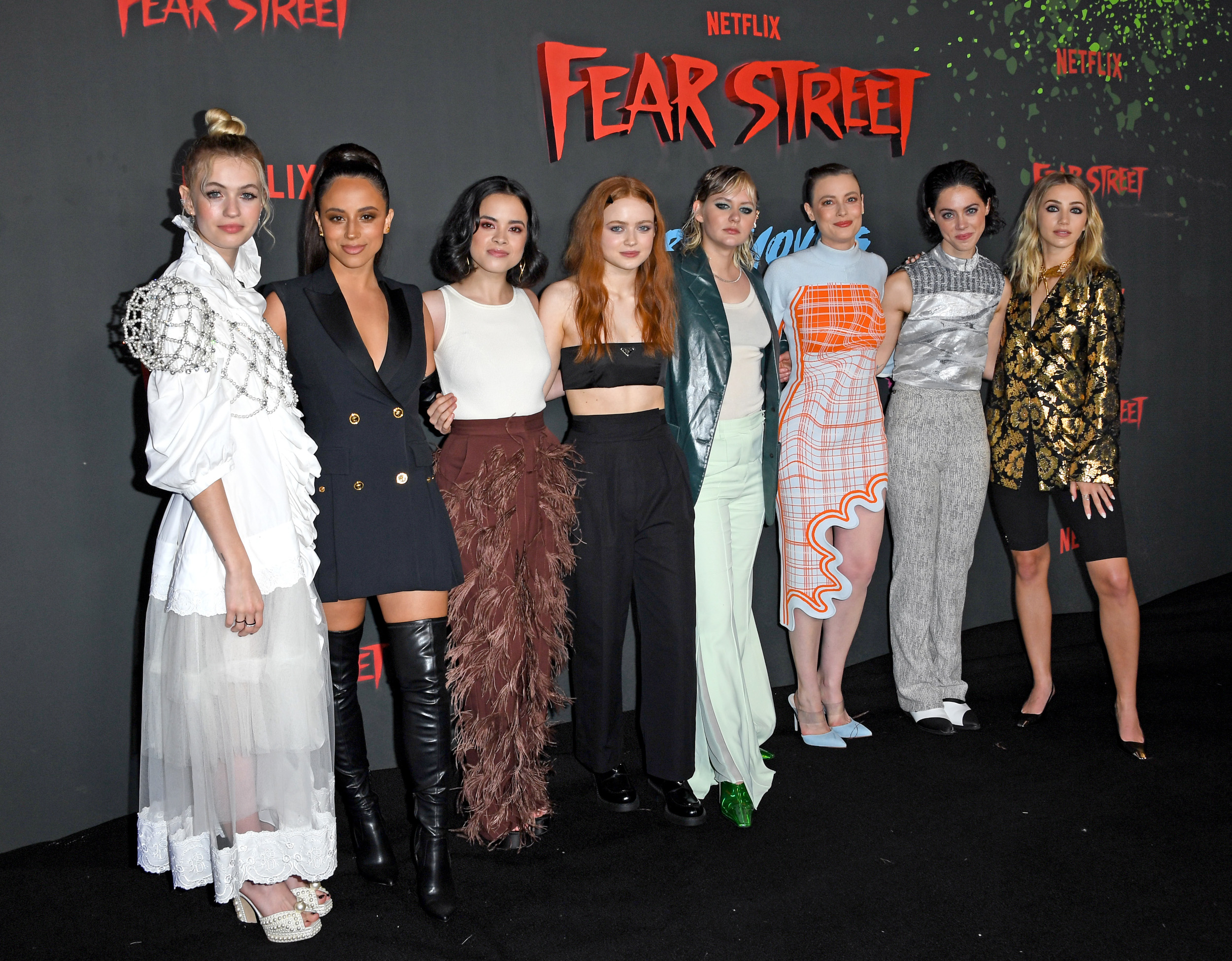 'Fear Street' stars Olivia Scott Welch, Kiana Madeira, Julia Rehwald, Sadie Sink, Ryan Simpkins, Gillian Jacobs, Elizabeth Scopel, and Emily Rudd stand in a row wearing dresses and suits