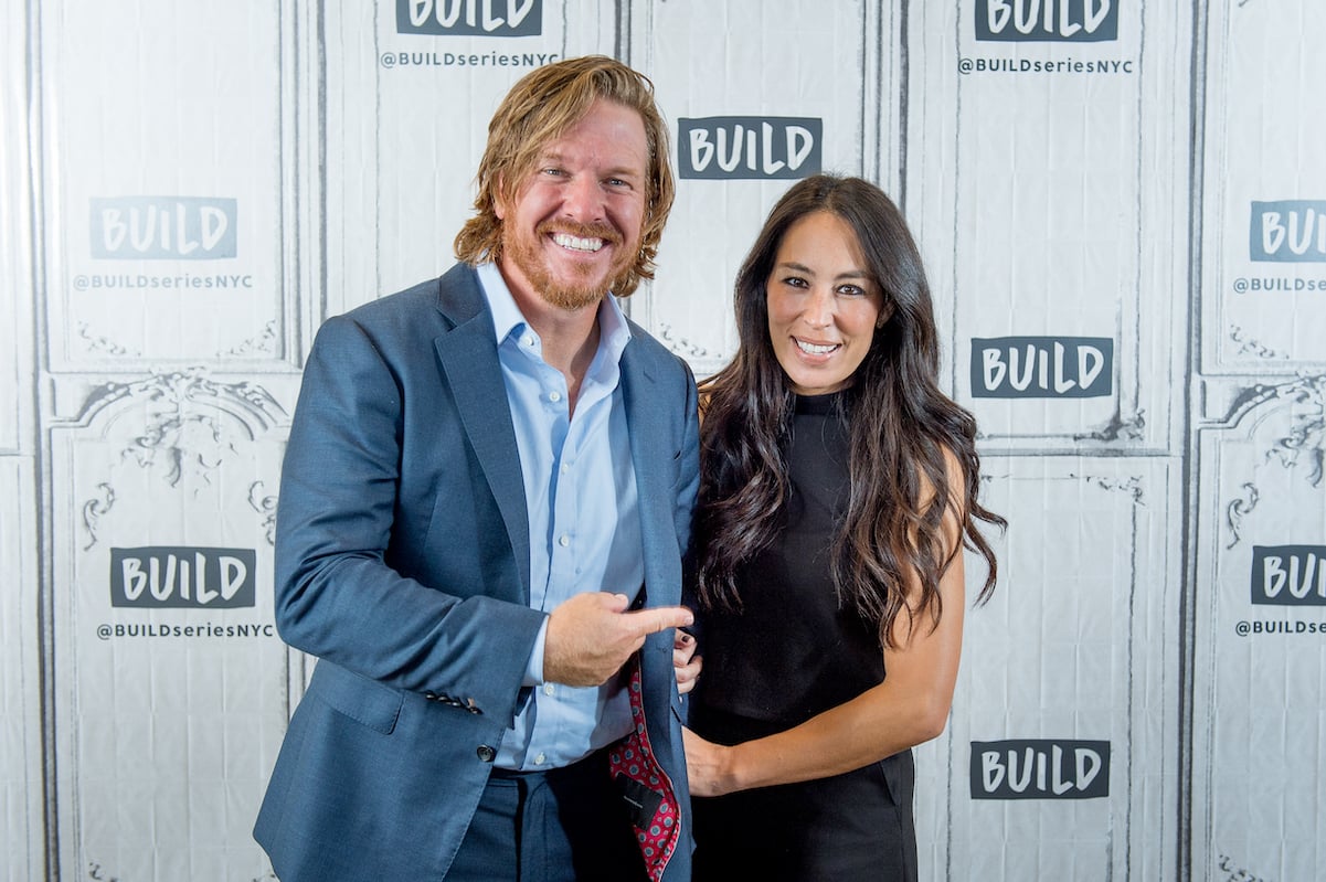 Chip Gaines points to Joanna Gaines as she holds onto his arm while they pose during a 2017 event.