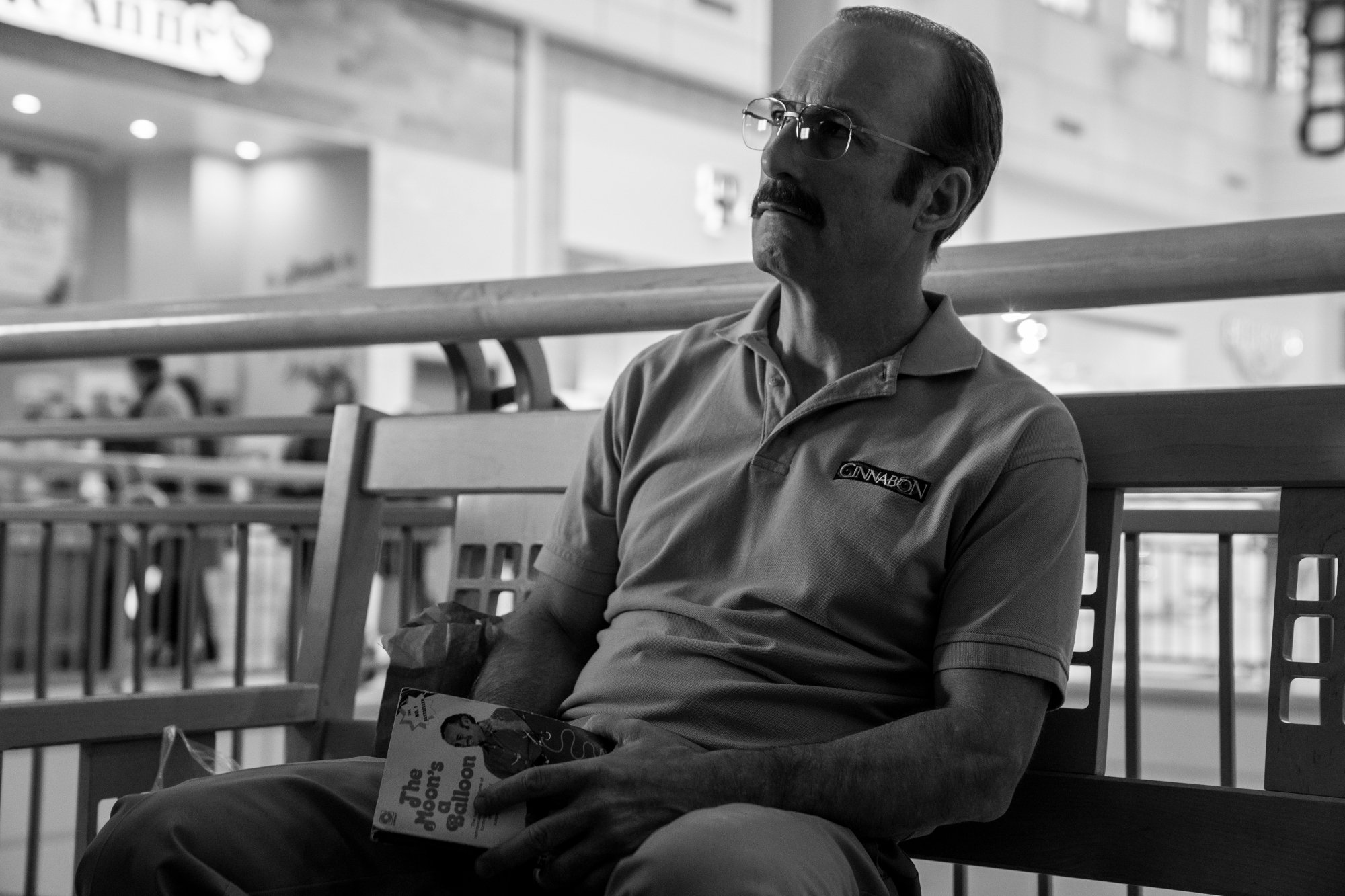 A black and white image of Bob Odenkirk in 'Better Call Saul' - He's playing an older version of Saul Goodman who is sitting on a bench
