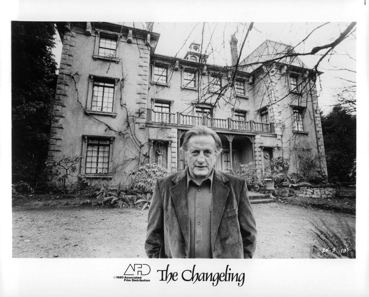 Actor George C. Scott standing in front of mansion