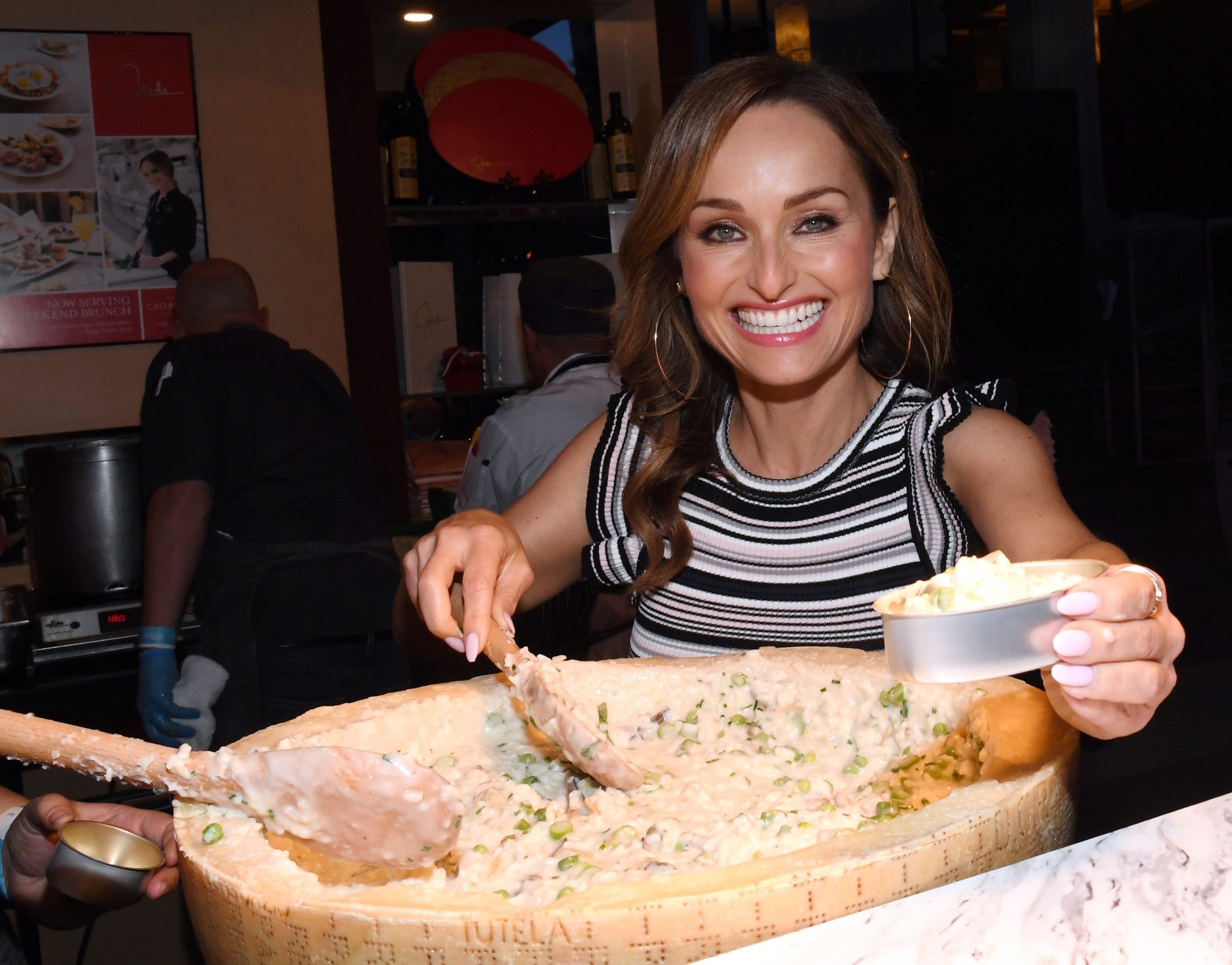 Food Network star Giada De Laurentiis smiles at the camera as she prepares a recipe, 2019