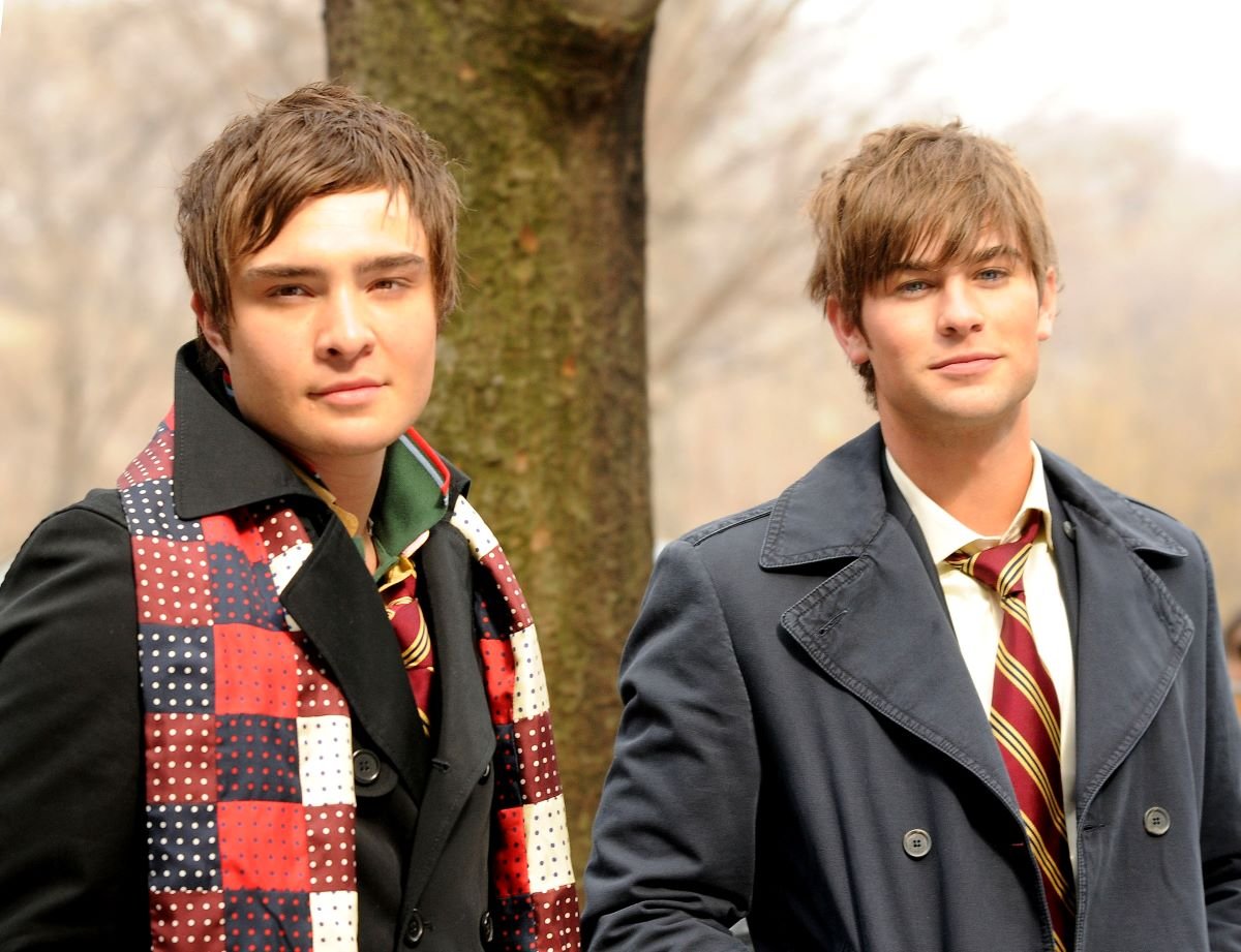 Ed Westwick as Chuck Bass wears a jacket and scarf and Chace Crawford as Nate Archibald wears a school uniform by a park in 'Gossip Girl'