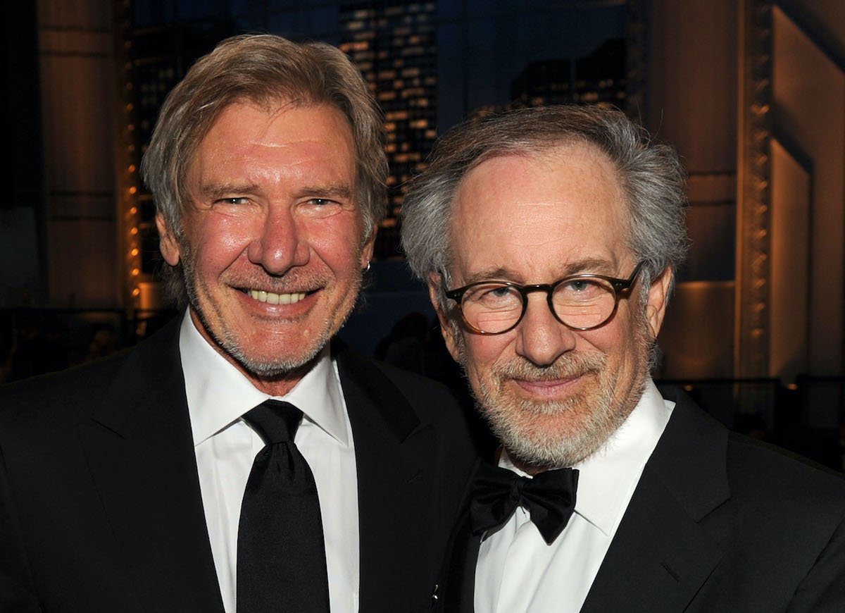 Harrison Ford and Steven Spielberg smile and pose while wearing suits