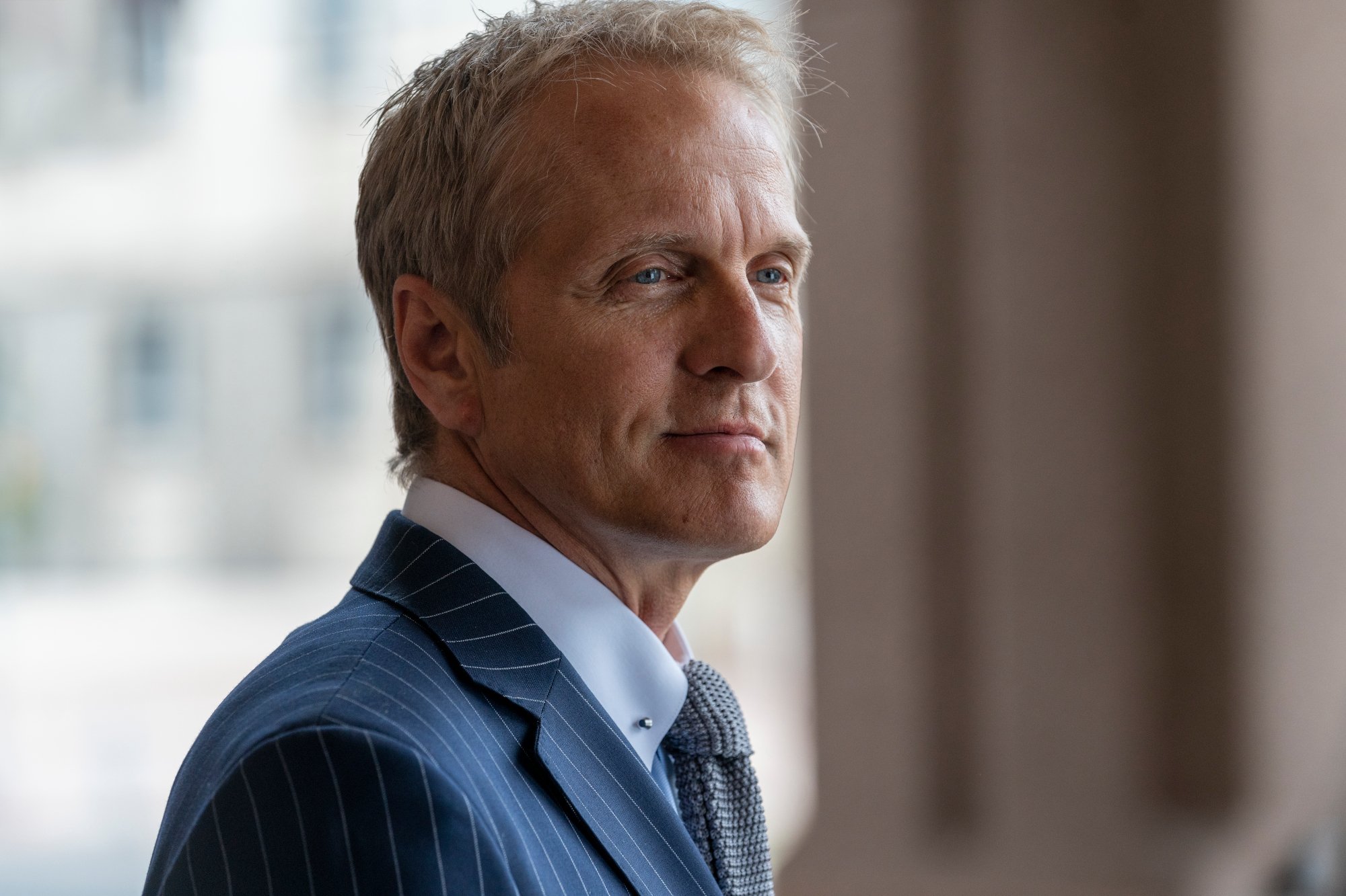 Patrick Fabian as Howard Hamlin in 'Better Call Saul' - He's wearing a blue suit and standing in front of a window