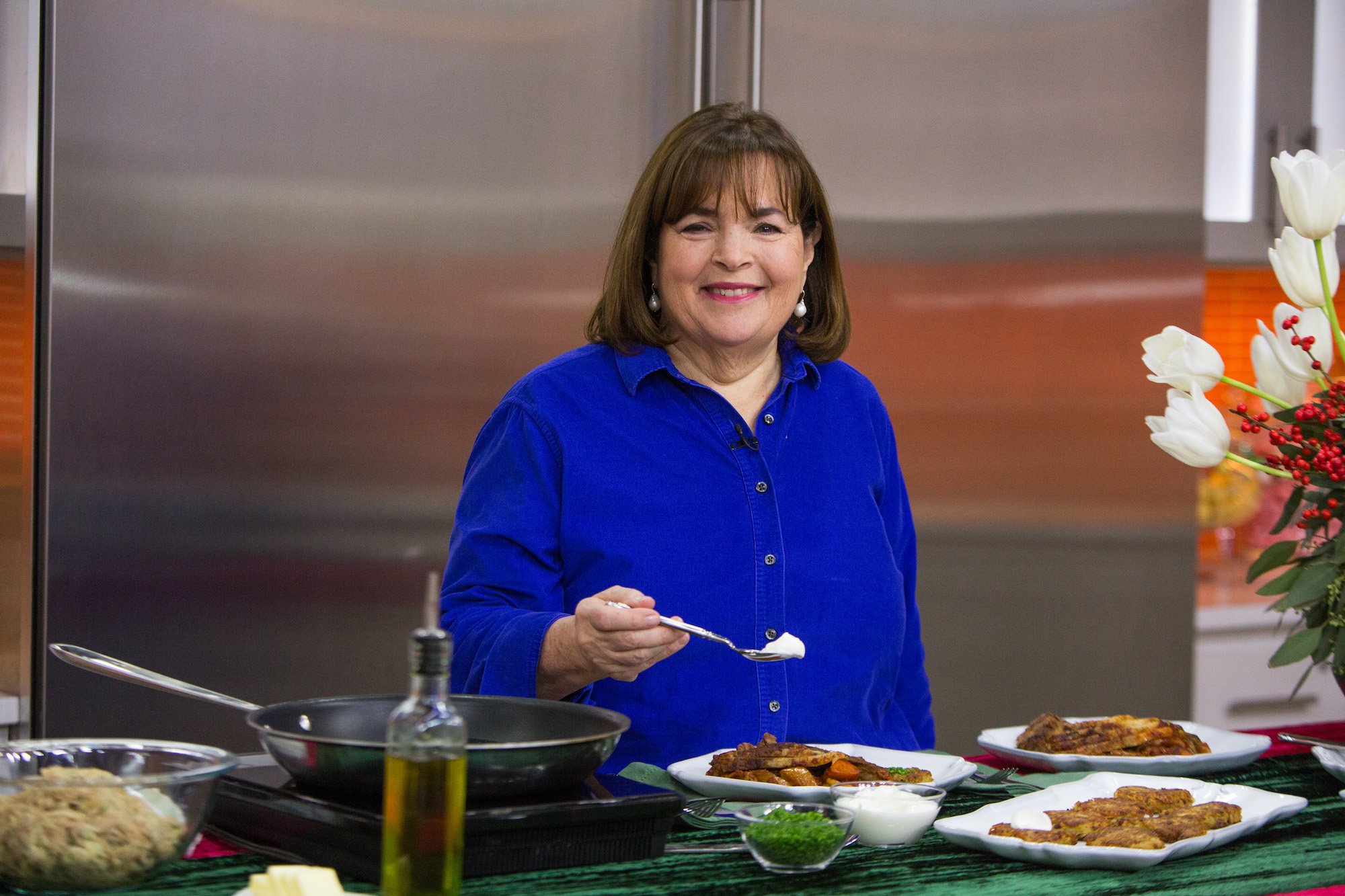 Ina Garten wears a bright blue shirt and smiles as she holds a spoon on the set of 'Today'