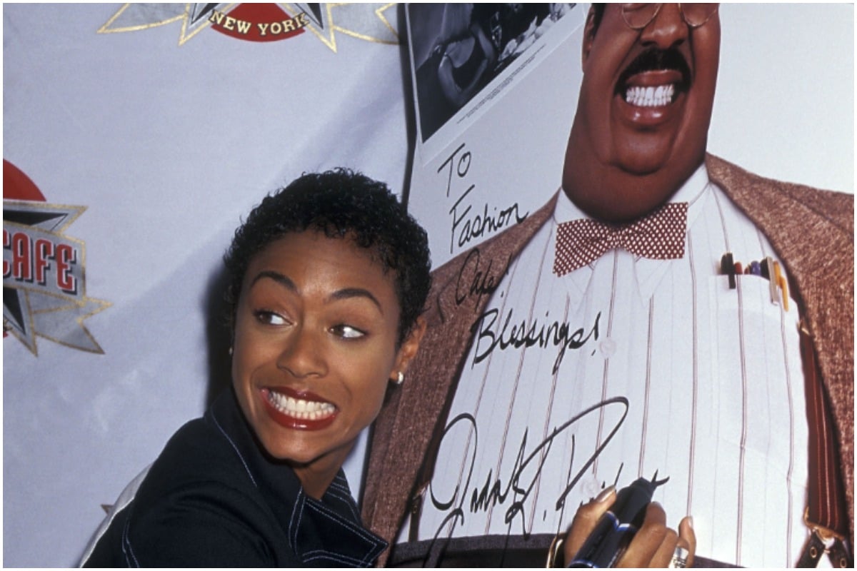 Jada Pinkett Smith smiling away from the camera while signing a 'The Nutty Professor' poster.