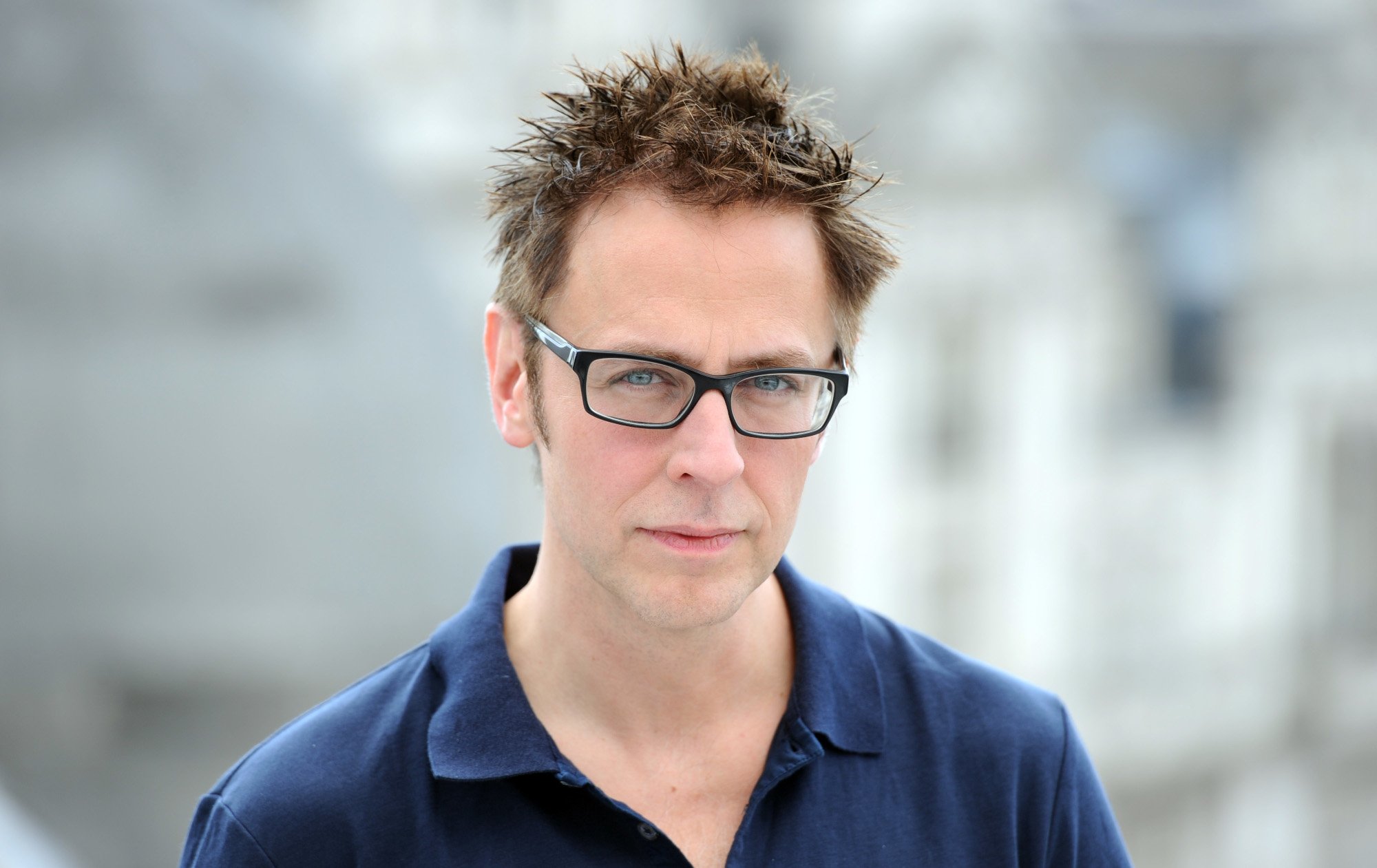 James Gunn, director of the Guardians of the Galaxy holiday special, wears a dark blue shirt and stands in front of a blurred white background