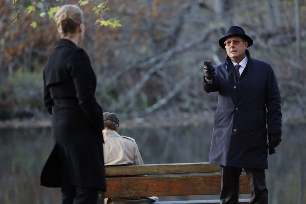 Laila Robins as Katarina Rostova stands outside while James Spader as Raymond 'Red' Reddington points a gun at her.