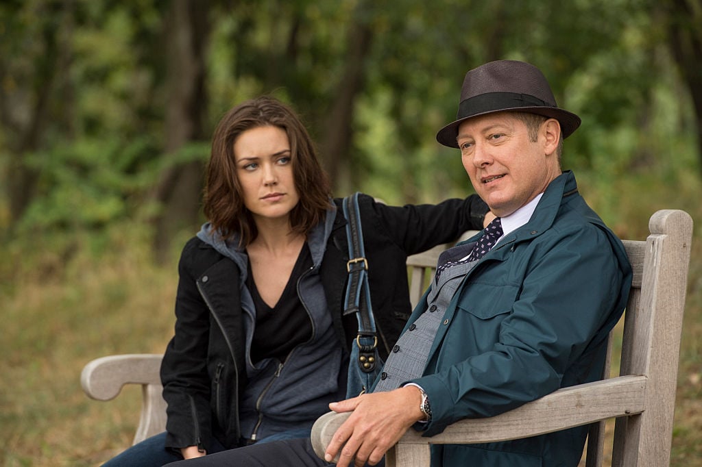 Megan Boone as Elizabeth Keen, James Spader as Raymond 'Red' Reddington sit on a park bench together.