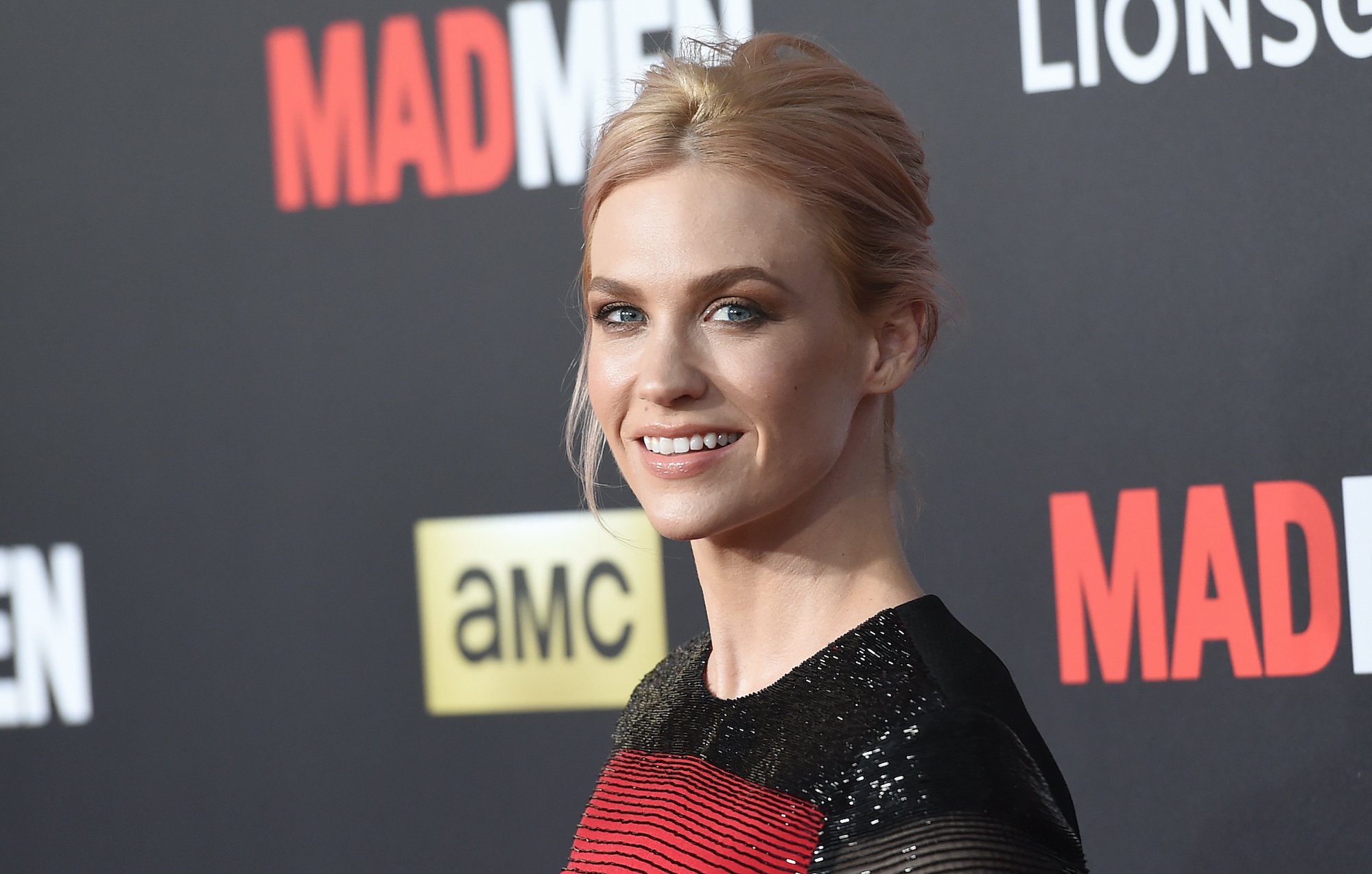 January Jones smiling in front of a black background