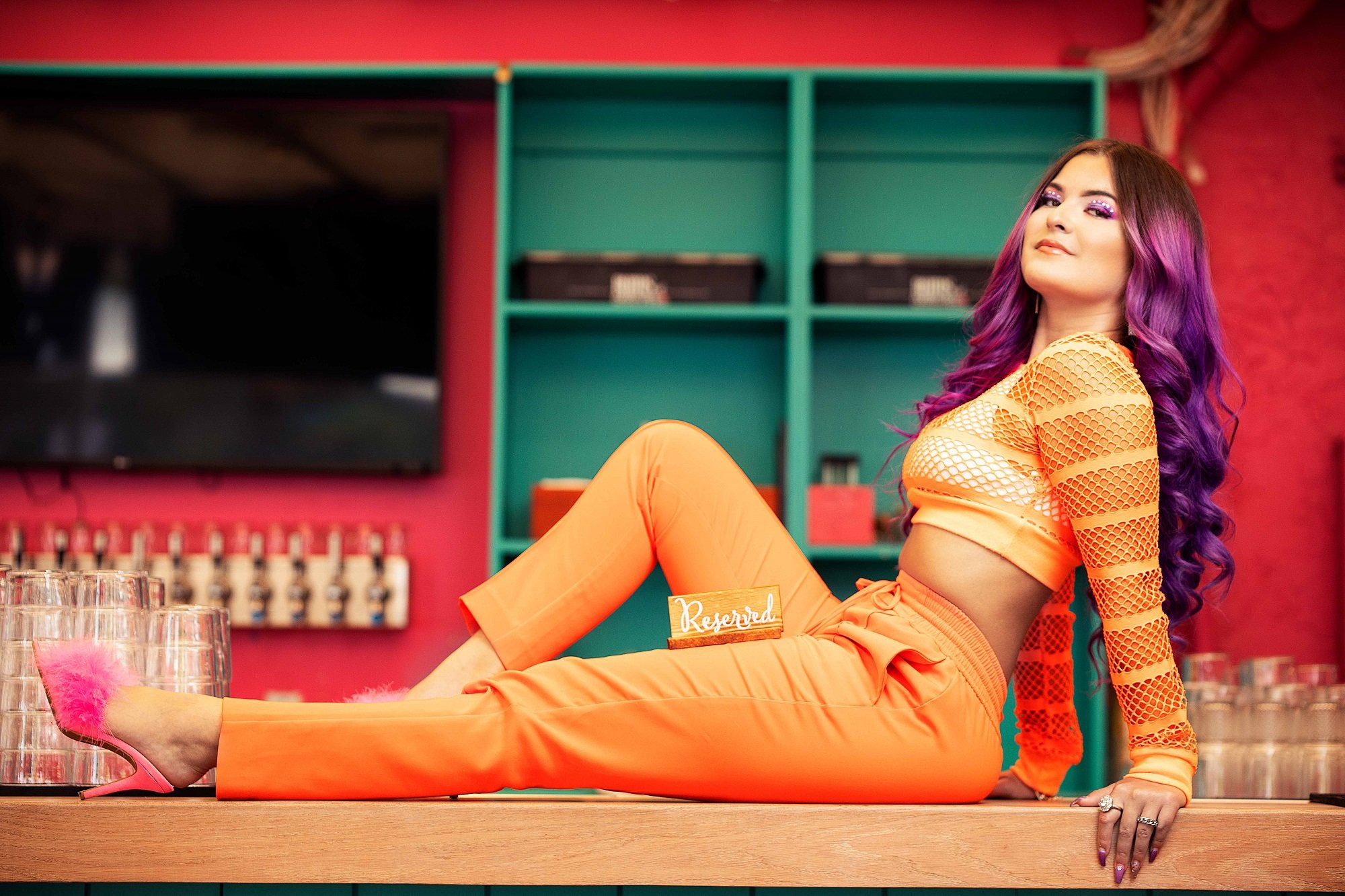 Singer Jasmine Ortiz sits on a bar and poses for a promotional photo for her single '21'