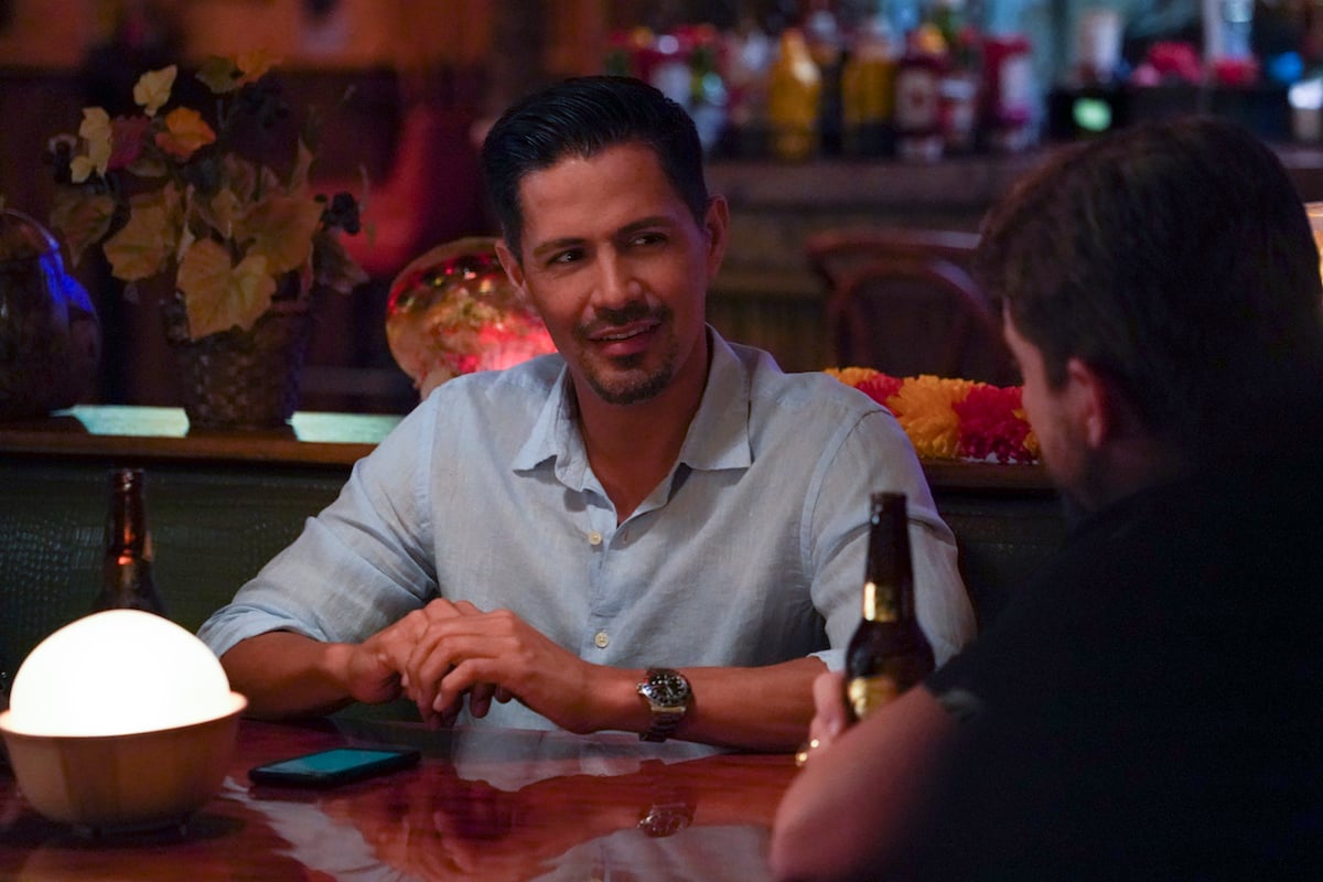 Jay Hernandez sitting at a table in 'Magnum PI' episode 