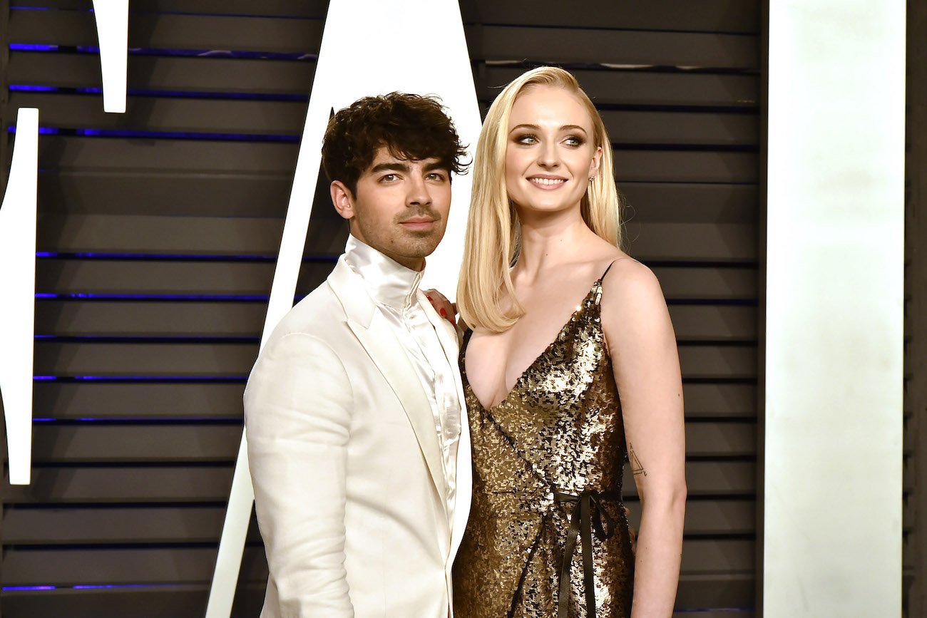 Joe Jonas and Sophie Turner standing next to each other in front of black and white background