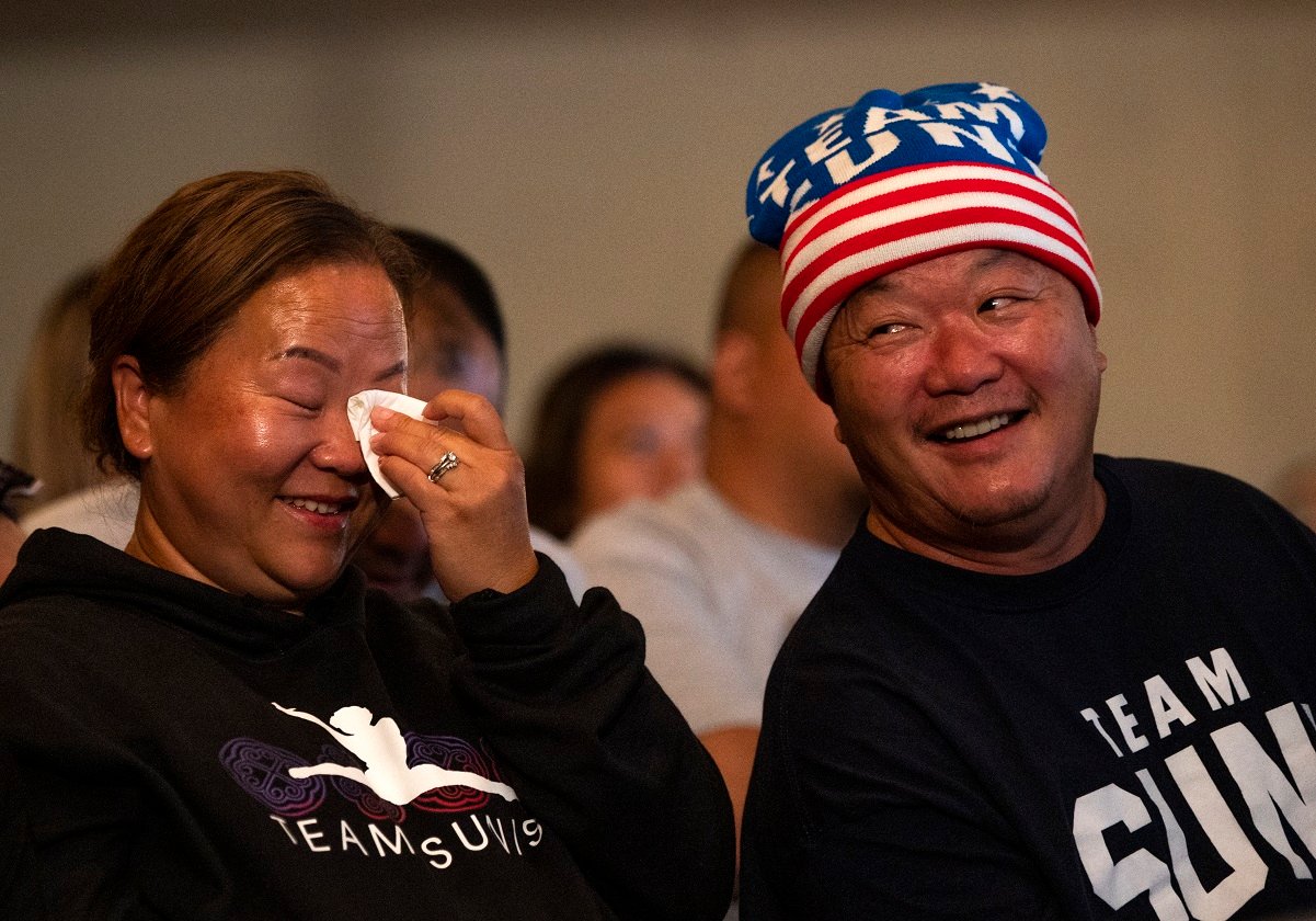 John Lee and Yeev Thoj reacting to their daughter competing on the balance beam