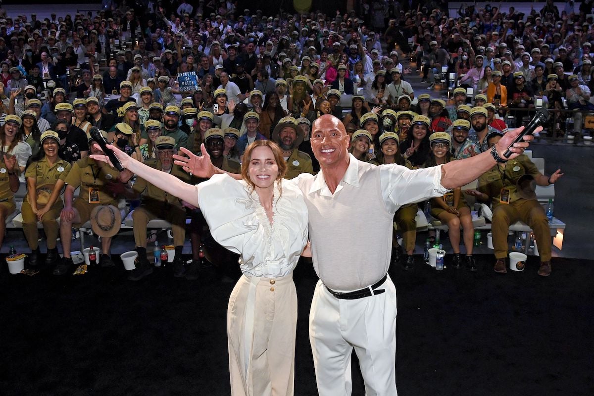Emily Blunt and Dwayne Johnson pose onstage with their arms wide open