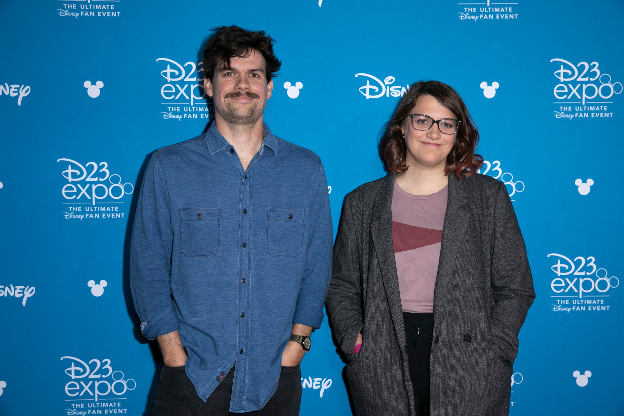 'Loki' writer Michael Waldron and director Kate Herron stand side by side in front of a blue Disney D23 Expo wall